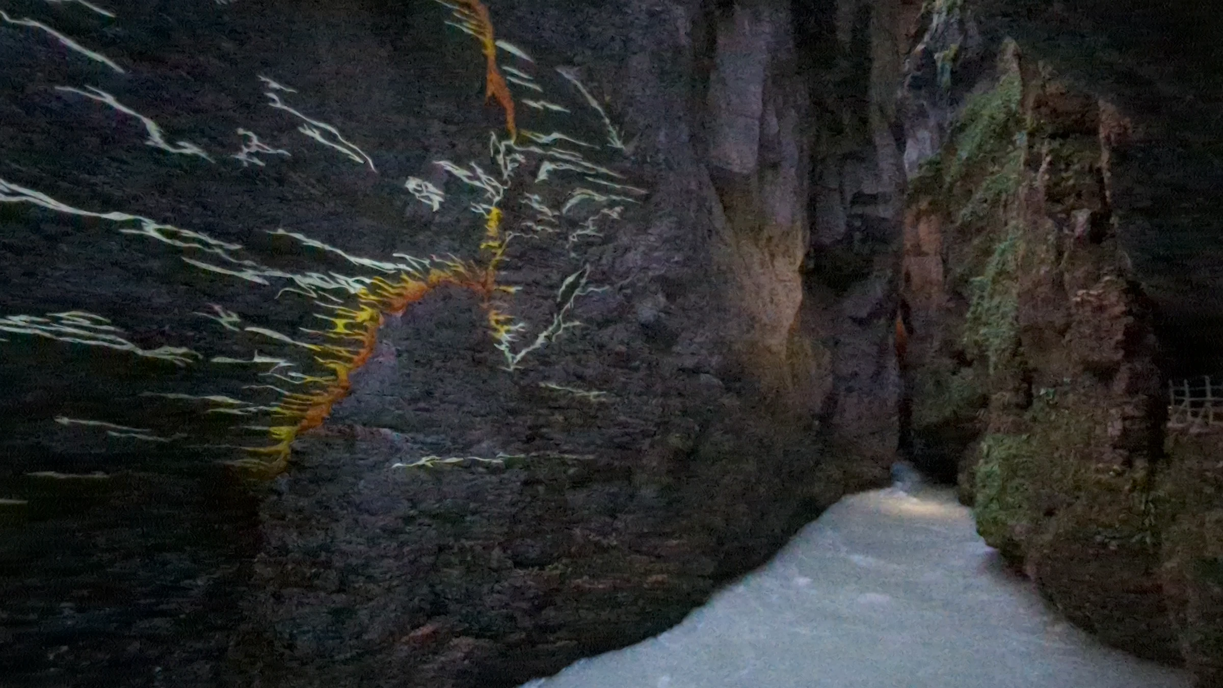 Farbige Lichtlinien auf der dunklen Felswand der Aareschlucht bei Nacht