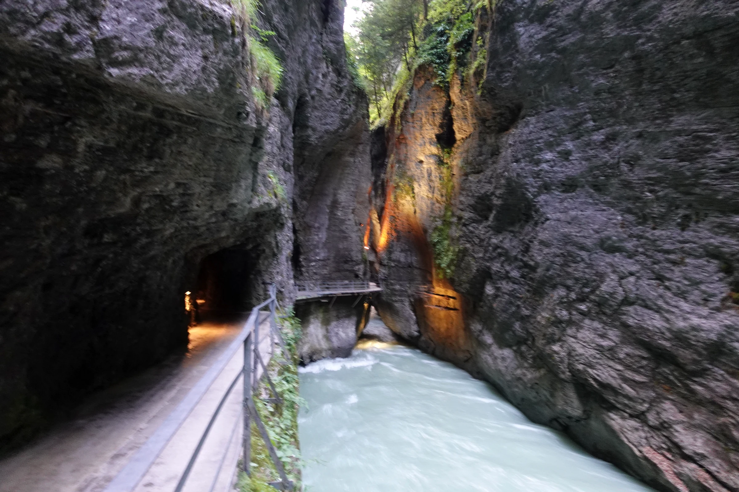 Beleuchteter Steg und Tunneleingang neben der tosenden Aare in der Aareschlucht bei Nacht