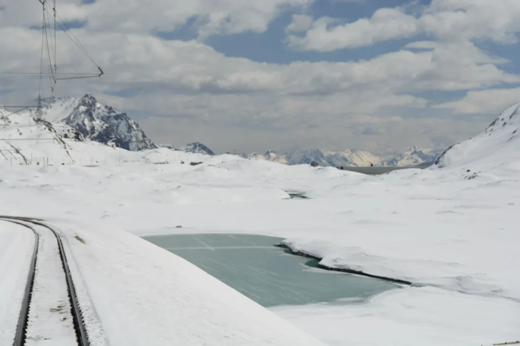 Frozen and snow-covered Lago Bianco seen through the window of the Bernina Express in spring