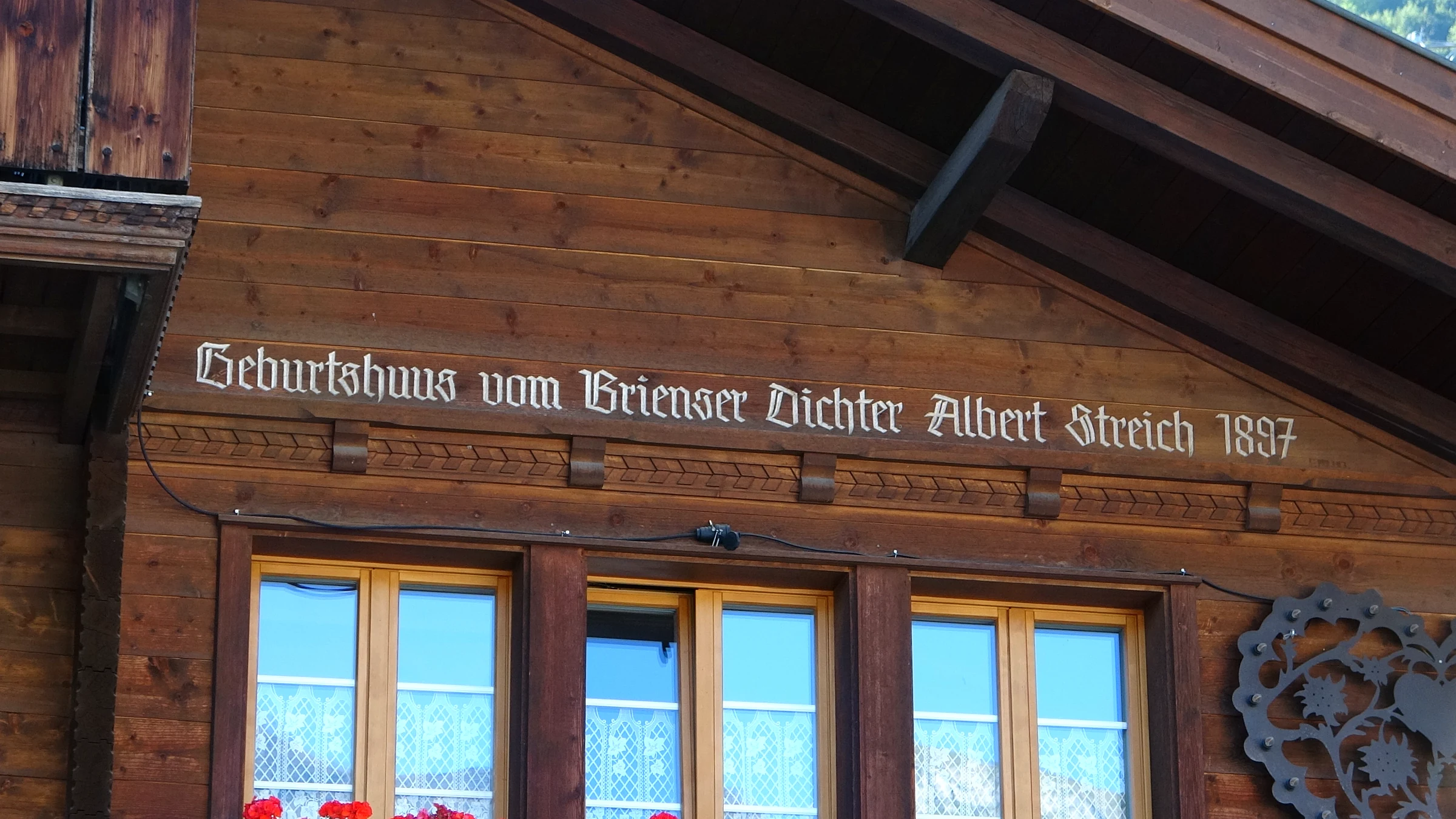 Aufgemalte Inschrift an einem Holzhaus: Geburtshaus vom Brienzer Dichter Albert Streich 1897