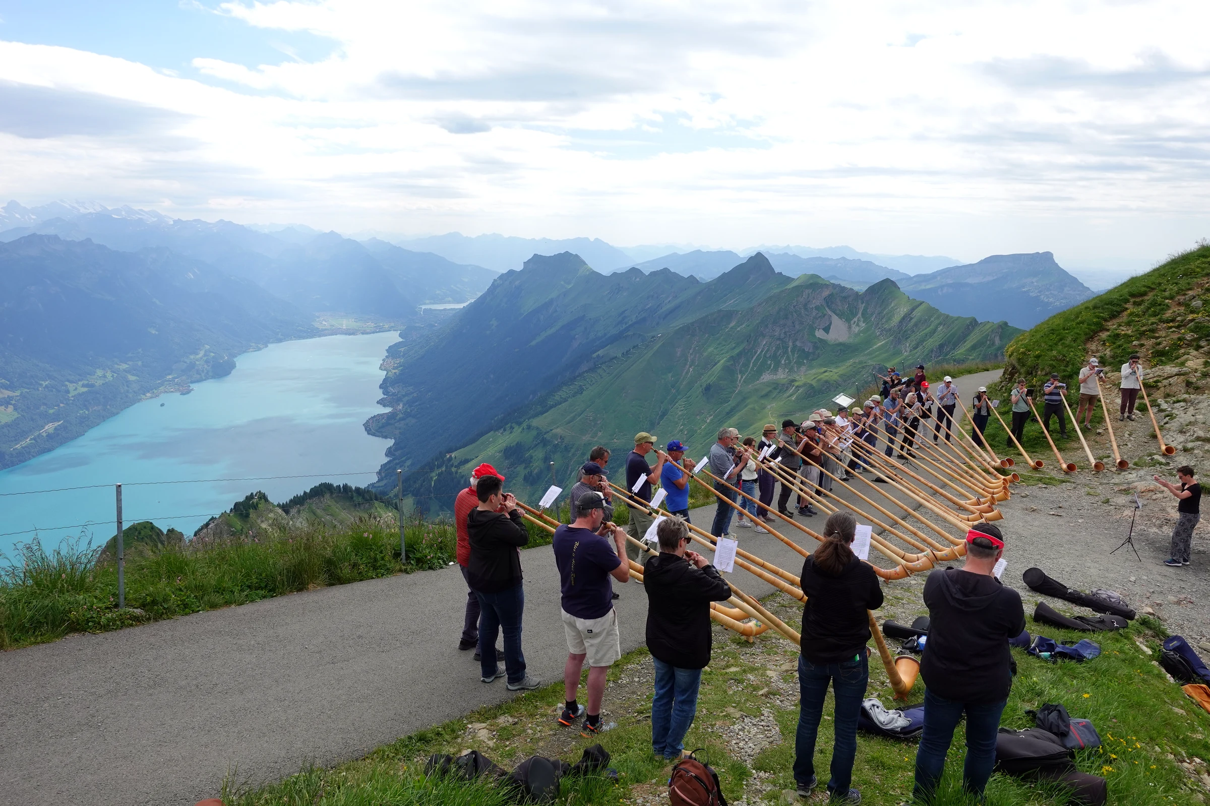 Alphornbläser in einer langen Reihe auf dem Weg unterhalb des Brienzer Rothorns, im Hintergrund der Brienzersee
