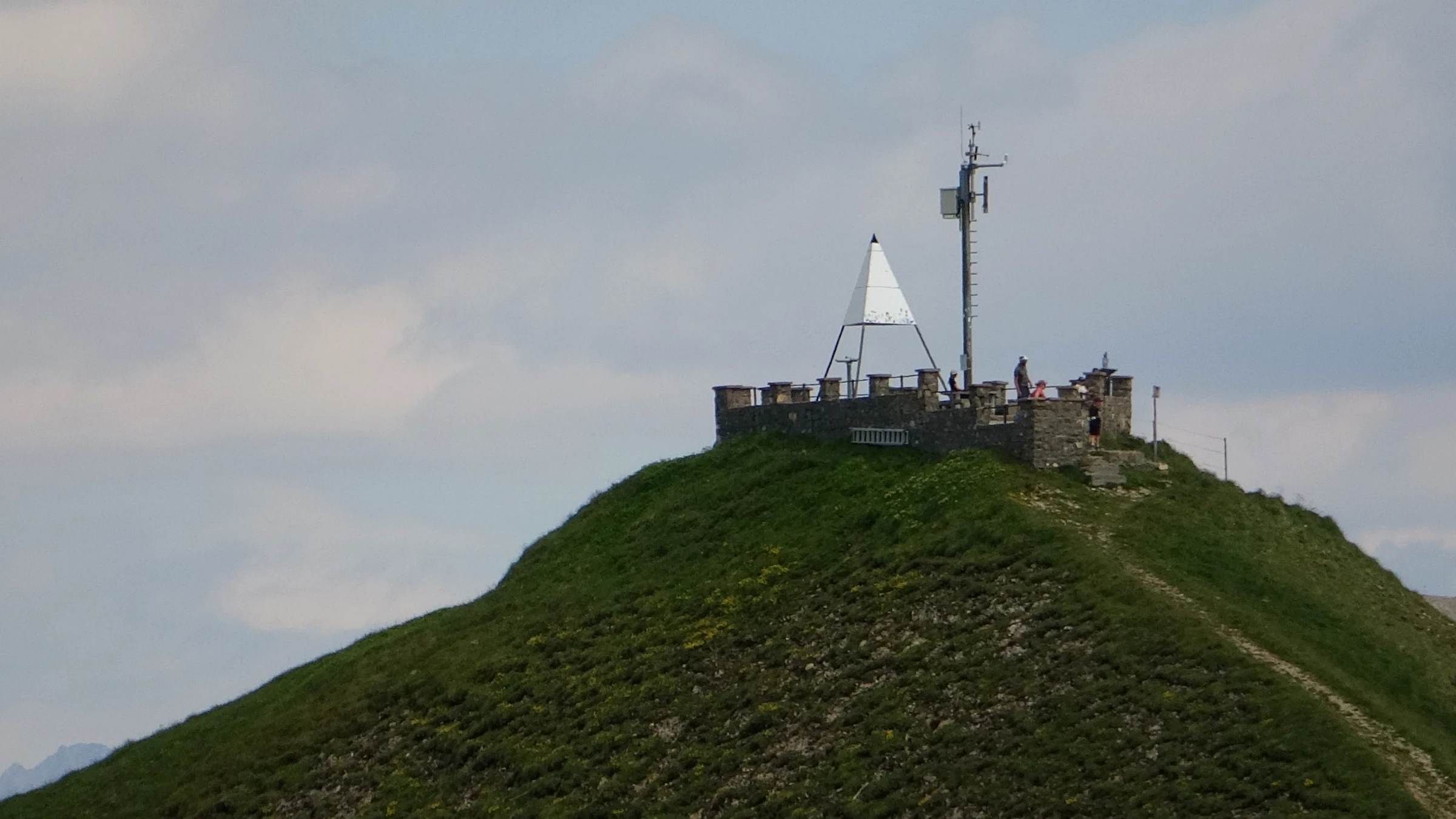 Steinerne Gipfelplattform des Brienzer Rothorns mit Vermessungszeichen und Antenne, von unten gesehen