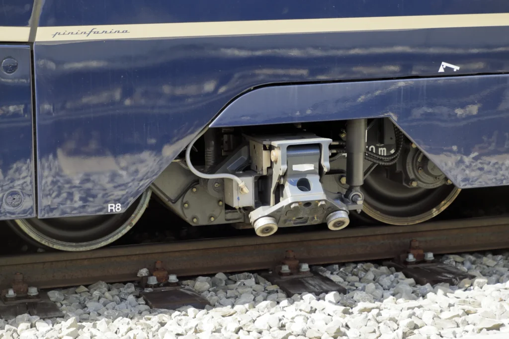 Nahaufnahme des Umspur-Drehgestells unter einem blauen Wagen des GoldenPass Express