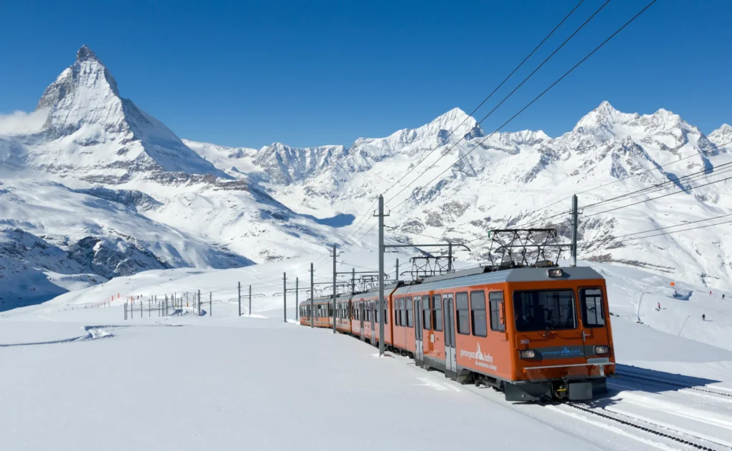 Red Gornergrat Railway train on a snowy slope between Rotenboden and Gornergrat with the Matterhorn behind