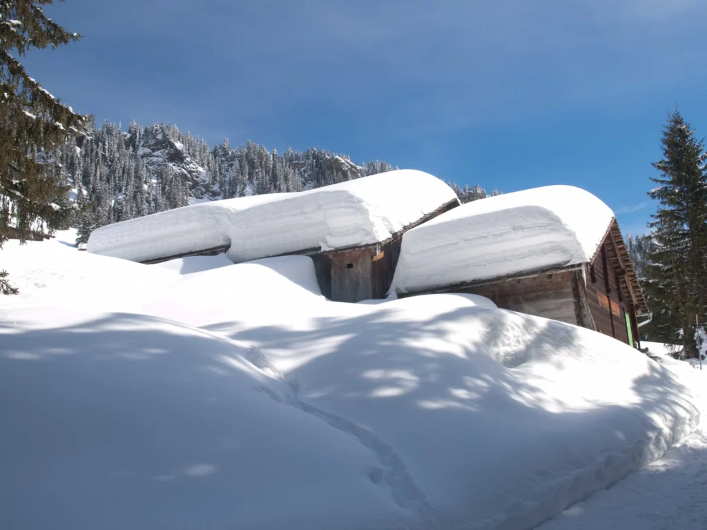 Alte Holzchalets unter dickem Schnee an einem sonnigen Wintertag in Grindelwald