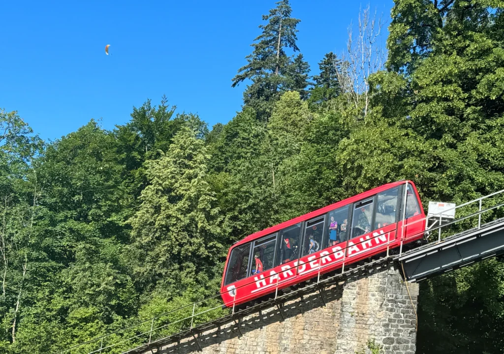 Red Harderbahn funicular car on a stone viaduct in the forest above Interlaken