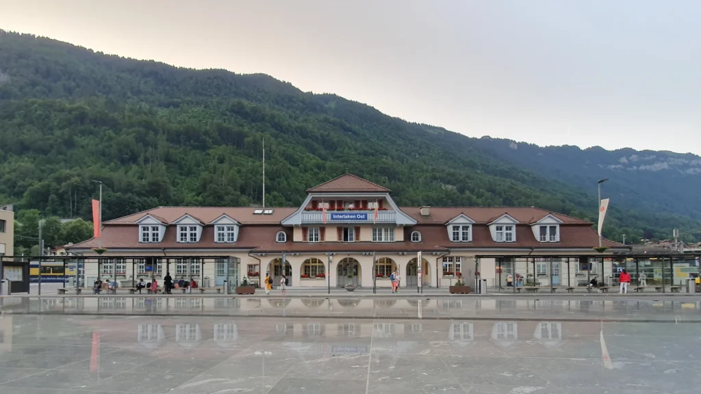 Interlaken Ost railway station building with its wooden facade and a large forecourt in the evening