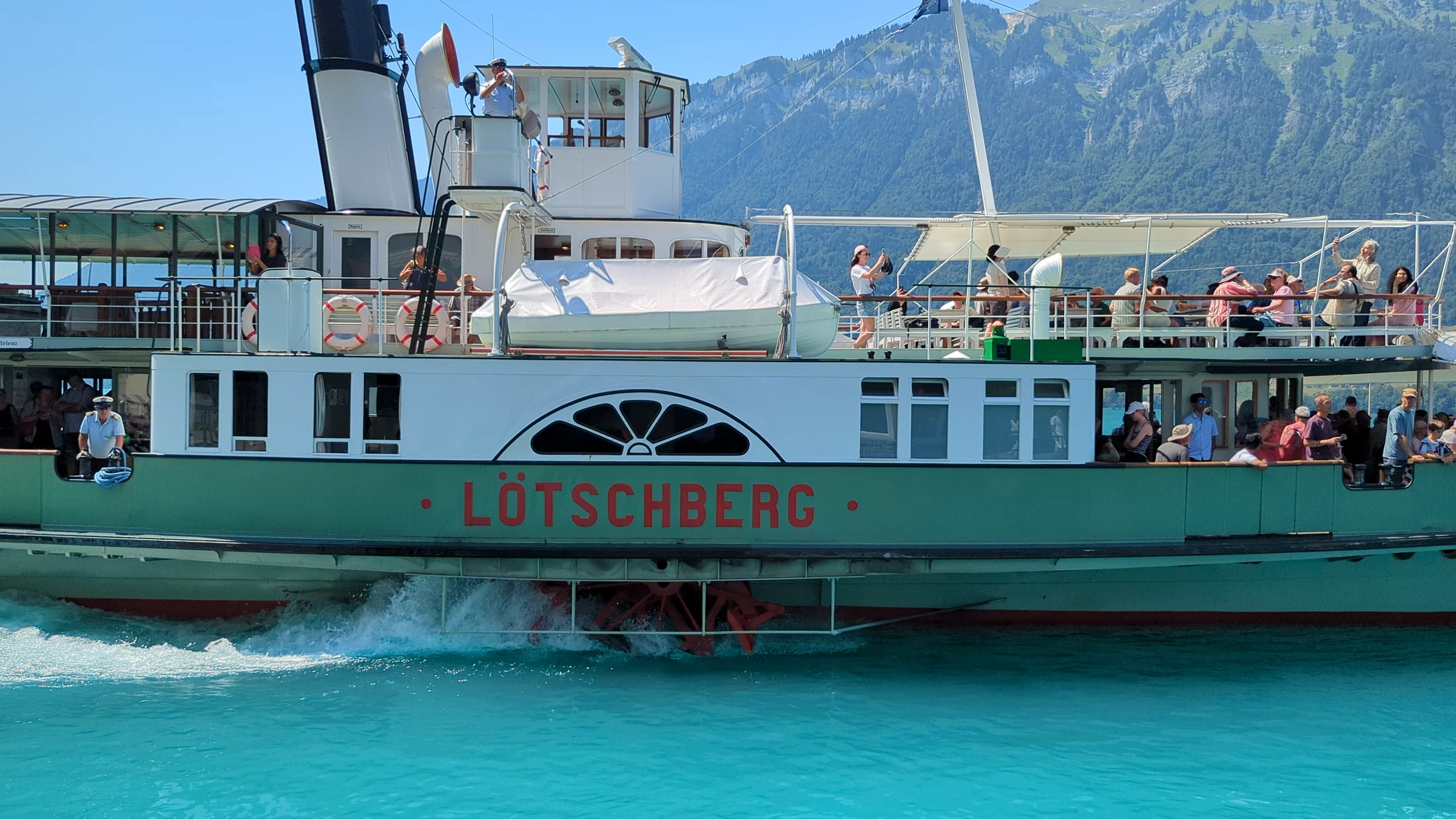 The historic paddle steamer Lötschberg leaving Iseltwald, paddle wheel churning the turquoise water