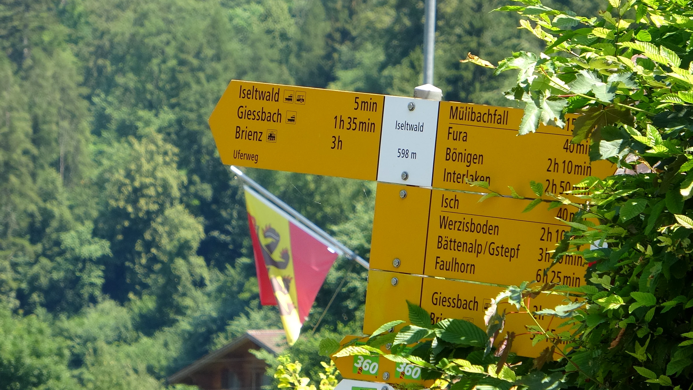 Yellow hiking signpost in Iseltwald at 598 m with times to Giessbach and Brienz on the lakeside trail