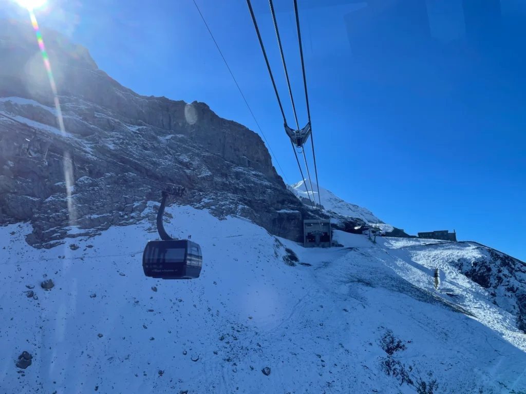 A cabin of the Eiger Express tricable gondola climbing next to the rock face of the Eiger above snowfields