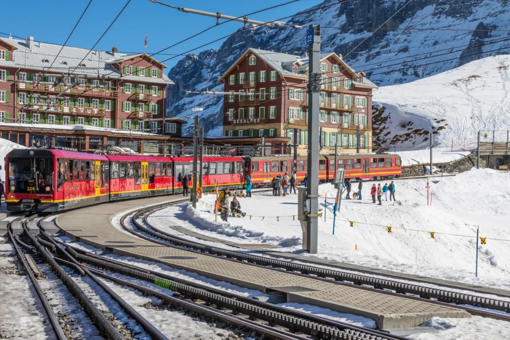 Red Jungfrau Railway trains waiting at Kleine Scheidegg station below the Eiger in the snow