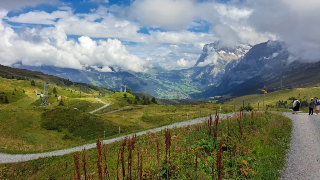 Gravel path from Kleine Scheidegg down into the green Grindelwald valley with the Wetterhorn under clouds