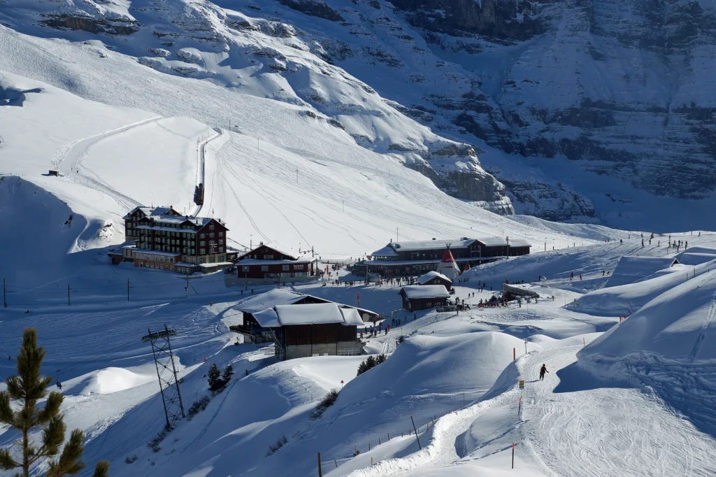 Kleine Scheidegg im tiefen Winterschnee mit Hotels, Bahnhof und präparierten Pisten unter den Bergen