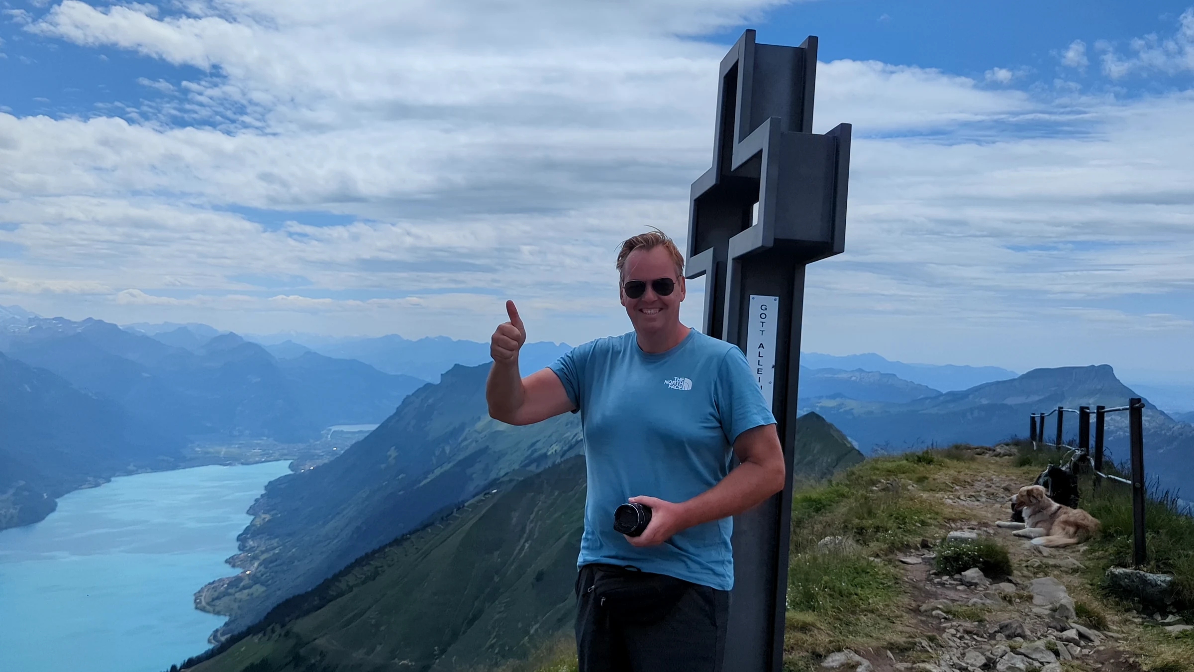 Autor Alexander Haselhoff am Gipfelkreuz des Brienzer Rothorns, unten der Brienzersee, Hund Miley ruht auf dem Weg