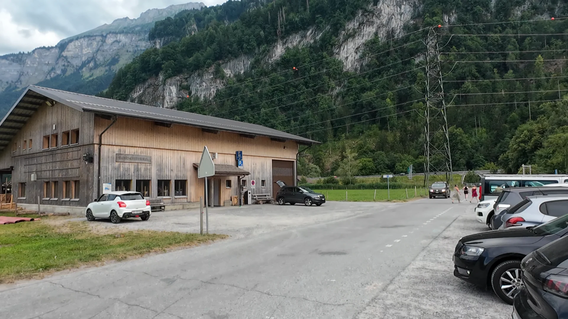 Parkplatz Wycheley Süd in Brienz mit grossem Holzgebäude und steilem bewaldetem Berghang dahinter