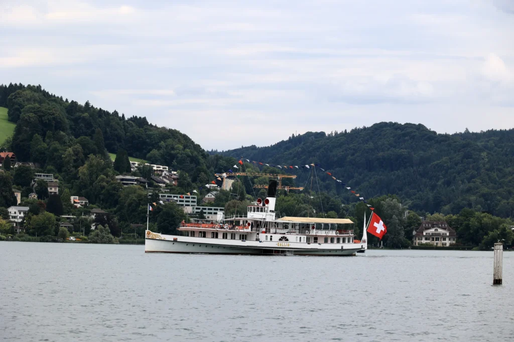 Paddle steamer Gallia on Lake Lucerne with wooded hills behind