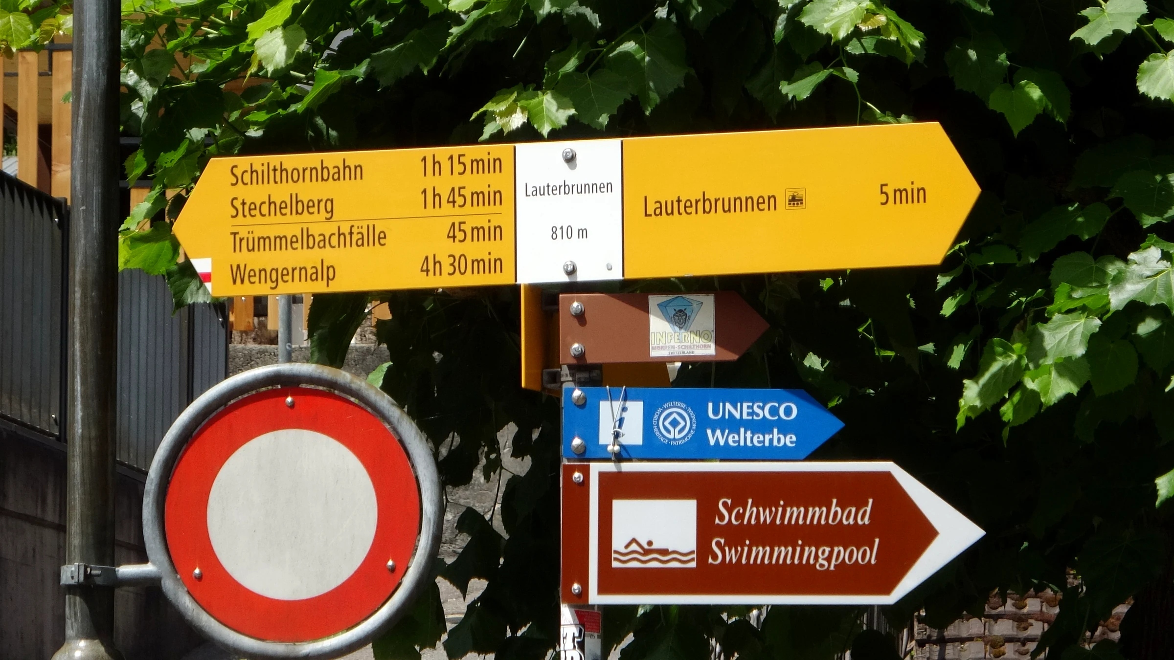 Yellow hiking signpost in Lauterbrunnen with walking times to Schilthornbahn, Stechelberg, Trümmelbachfälle and Wengernalp