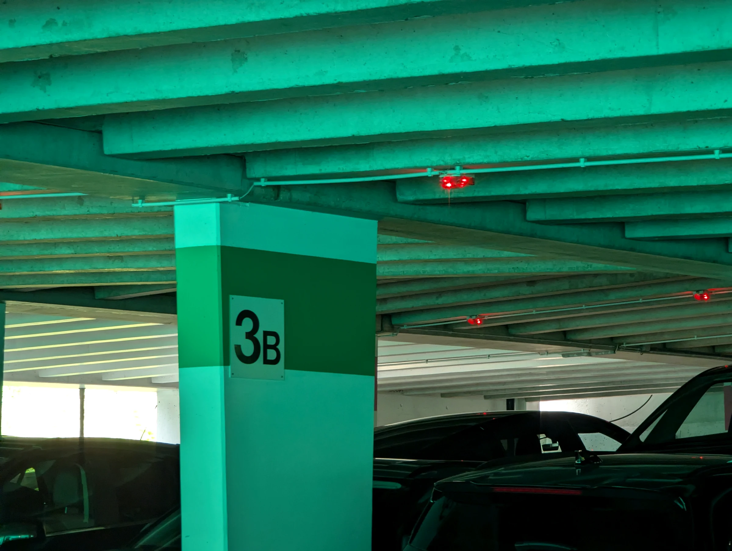 Green concrete pillar marked 3B inside the Parkhaus Lauterbrunnen with parked cars