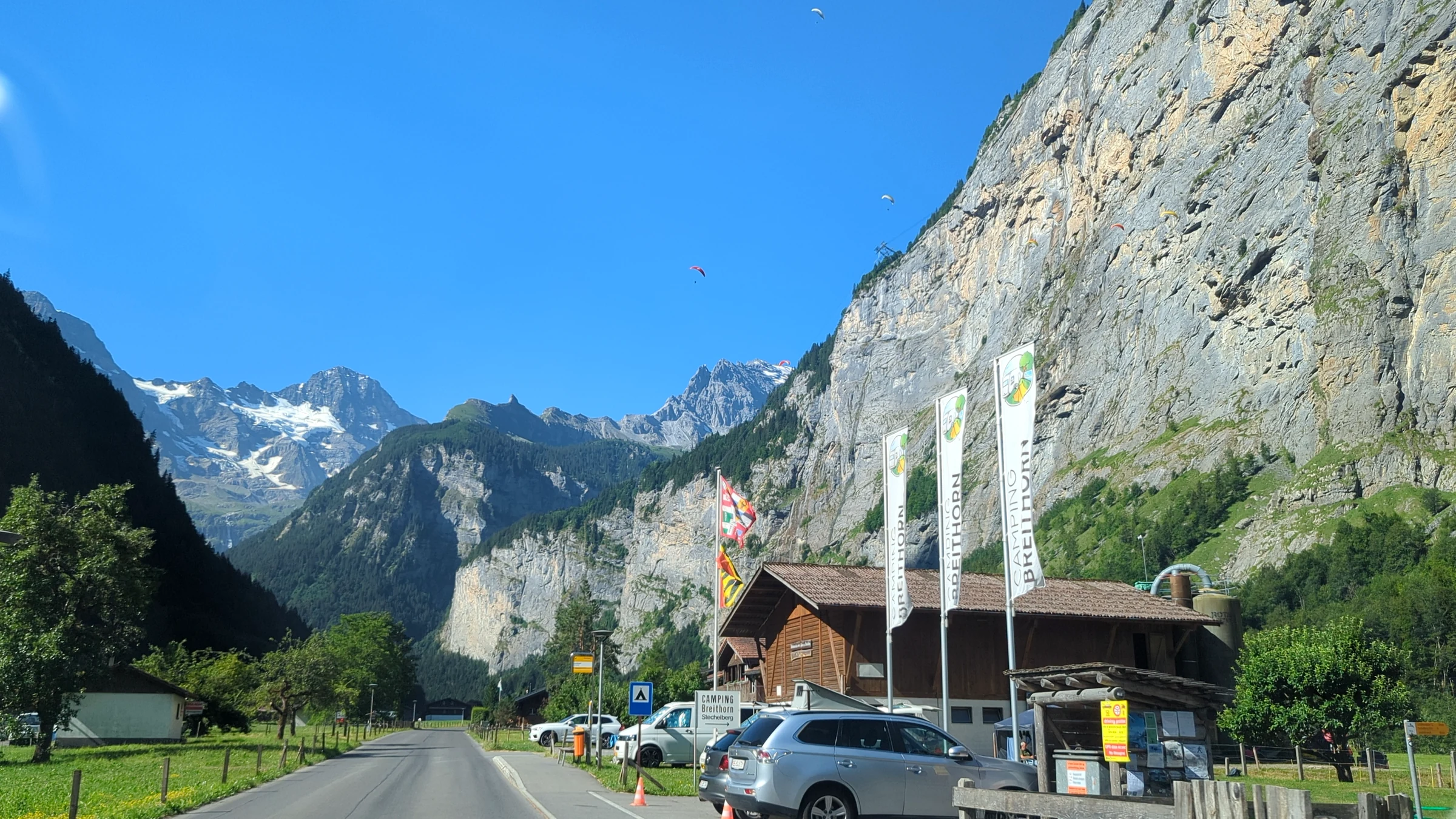 Road through the Lauterbrunnen Valley with the rock walls and snowy peaks at the head of the valley in morning sun
