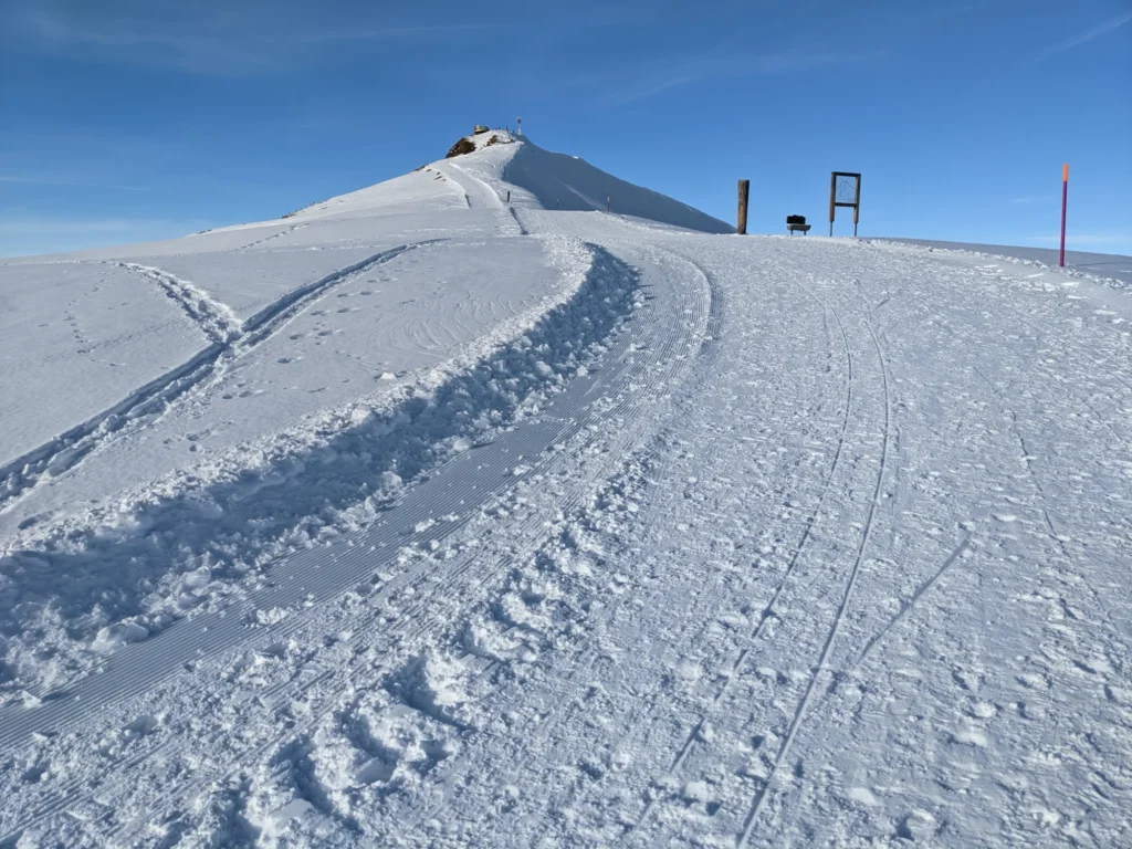 Verschneiter Weg des Royal Walk zum Aussichtspunkt auf dem Männlichen unter blauem Himmel