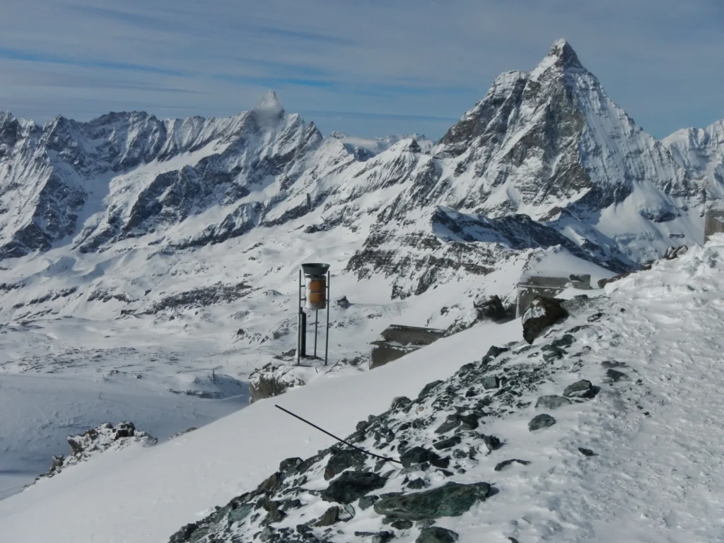 Snow-covered Matterhorn and surrounding peaks in winter seen from the Klein Matterhorn with a measuring instrument on the snowy ridge in the foreground