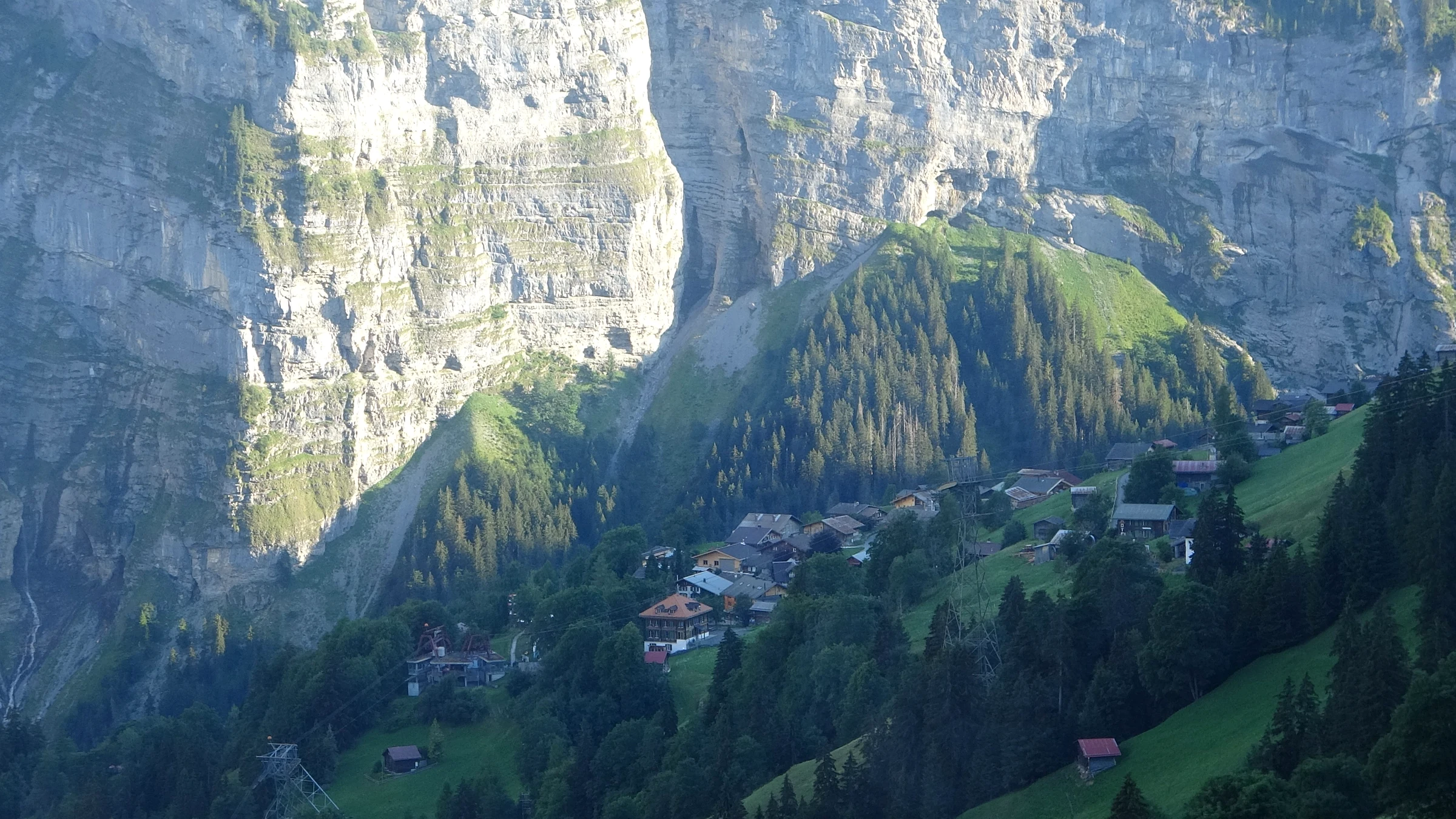 Chalets auf grünen Wiesen unterhalb der Felswände des Lauterbrunnentals, aus der Seilbahn gesehen