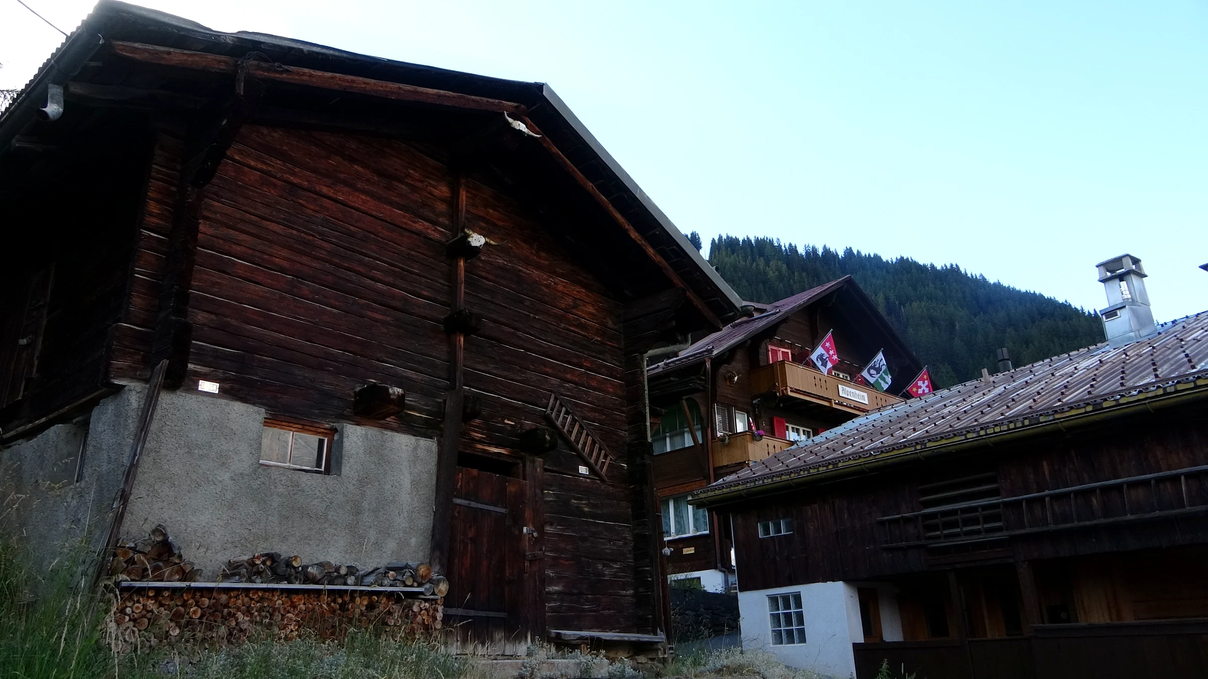 Alte, von der Sonne dunkel gebrannte Holzhäuser und ein Stall an einer Gasse in Mürren