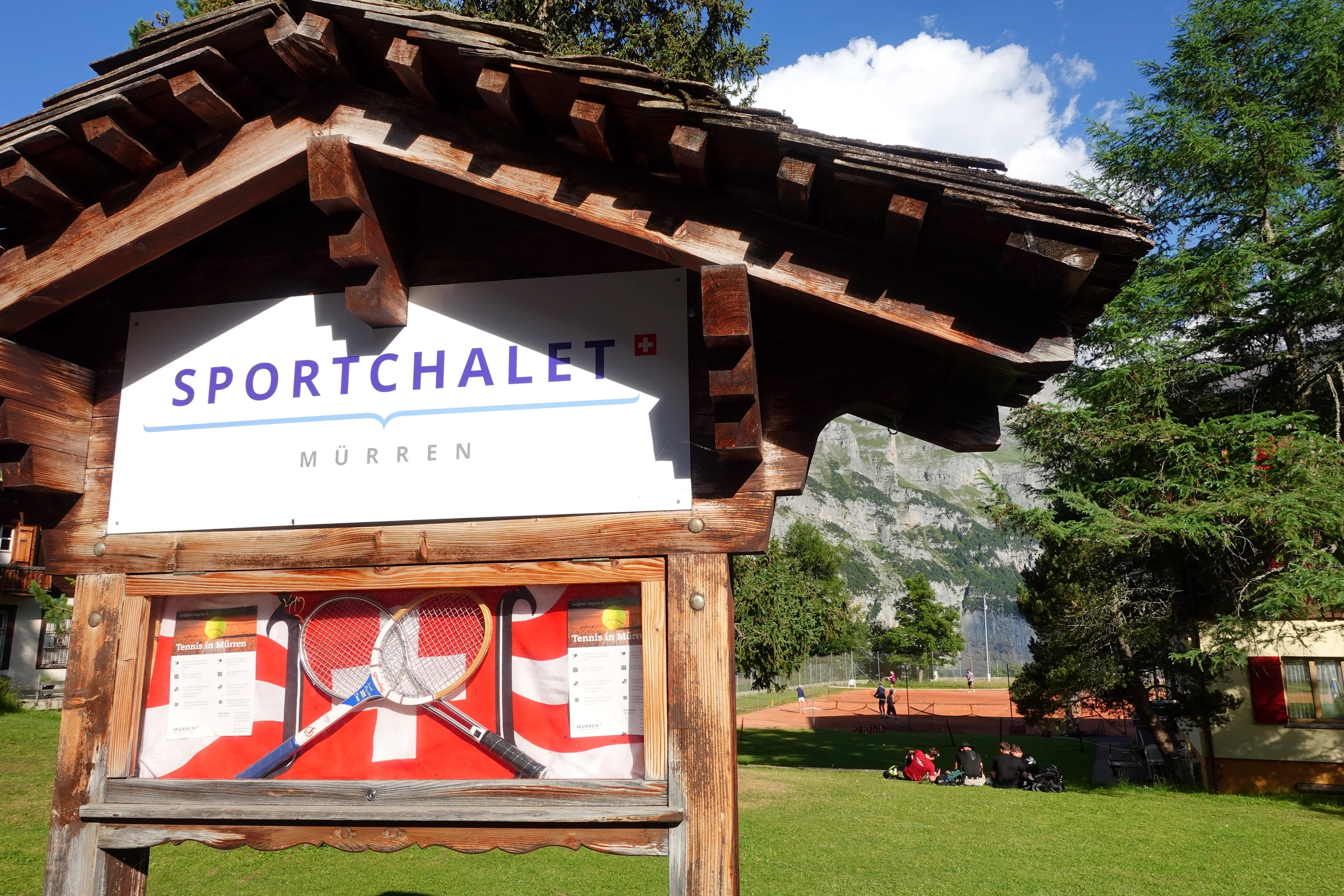 Holzschild Sportchalet Mürren mit gekreuzten Tennisschlägern vor den Tennisplätzen
