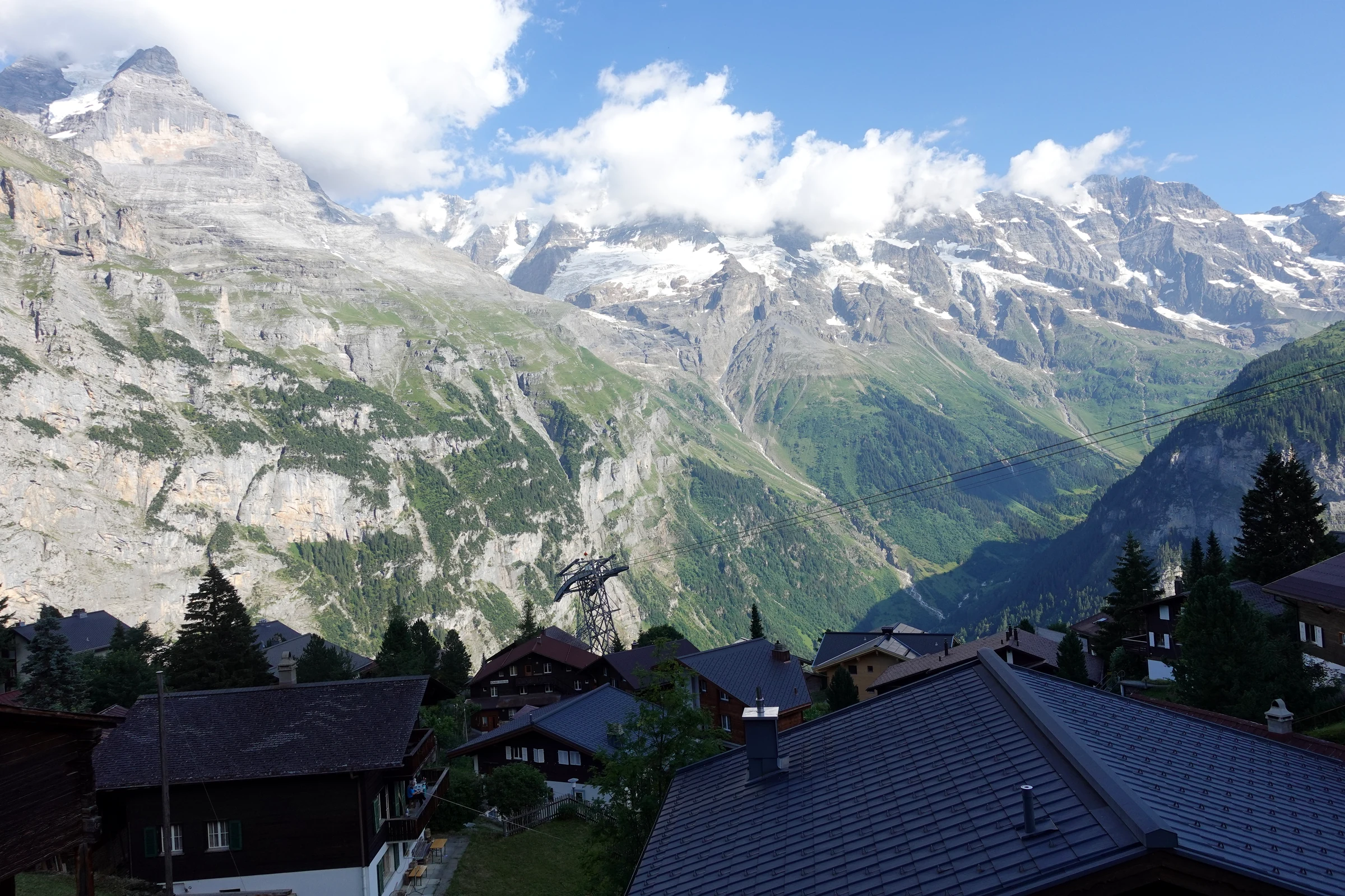 Dächer von Mürren über dem Lauterbrunnental mit vergletscherten Gipfeln und Wolken