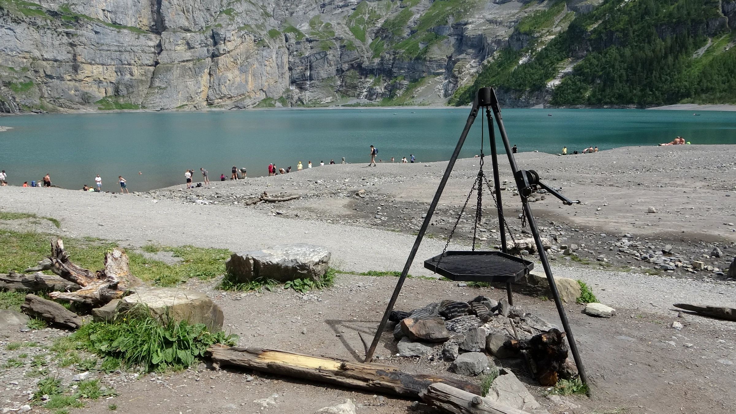 Offizielle Feuerstelle mit hängendem Grillrost am Dreibein über einem Kiesstrand am Oeschinensee