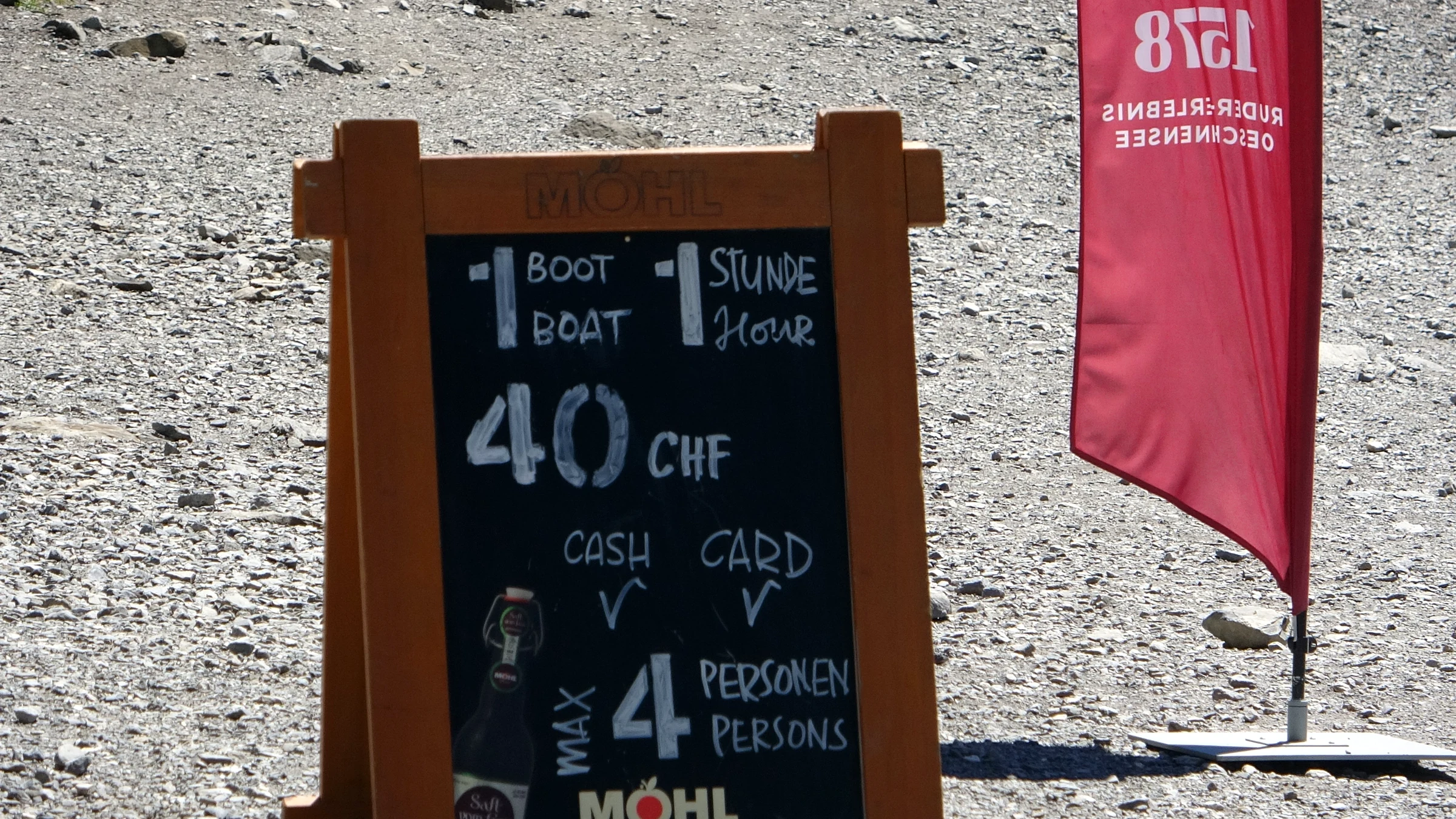 Kreidetafel am Bootsverleih Oeschinensee: 1 Boot, 1 Stunde, 40 CHF, bar und Karte, maximal 4 Personen