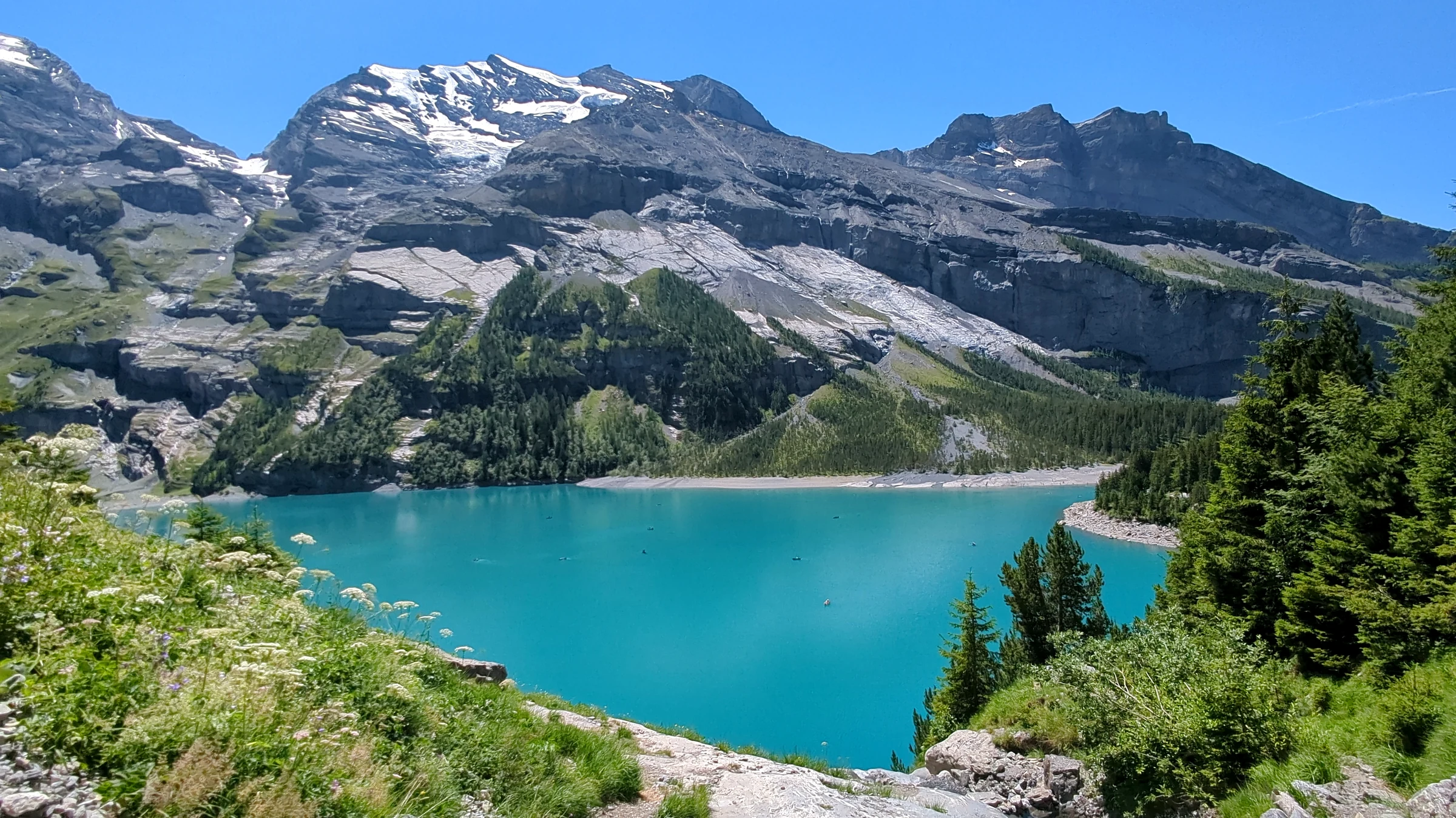 Oeschinen Lake seen from the trail above the north shore, turquoise water below snowy peaks