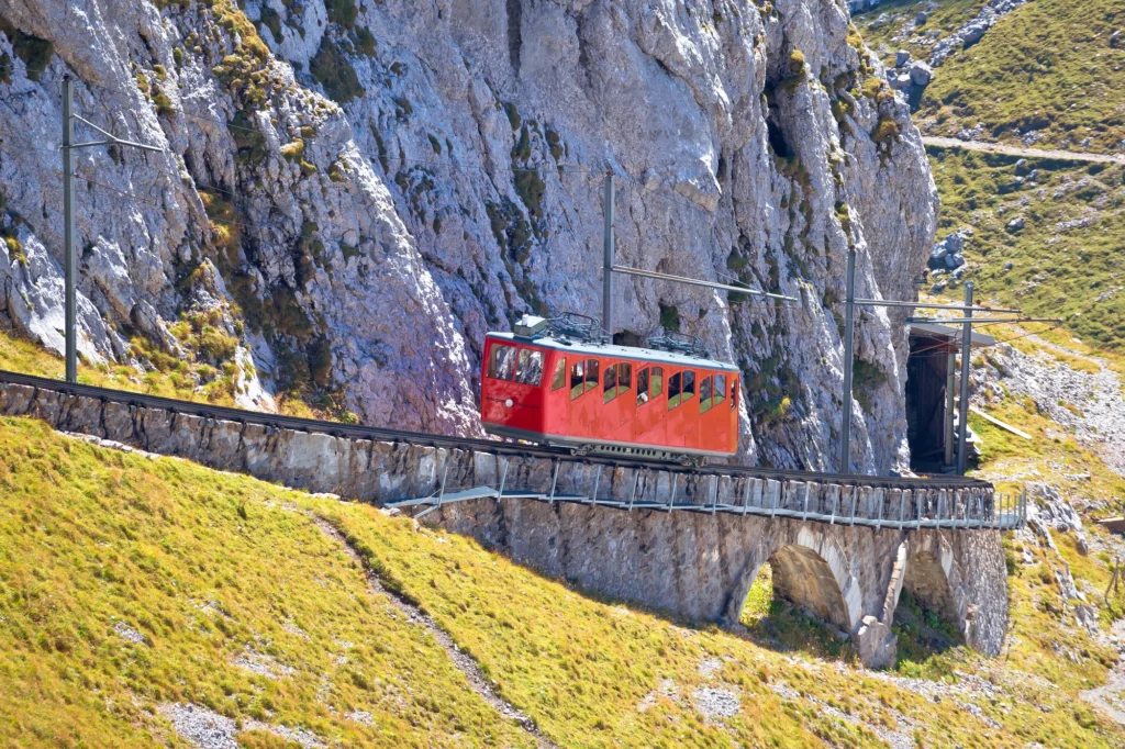 Roter Wagen der Pilatusbahn unter grauen Felswänden