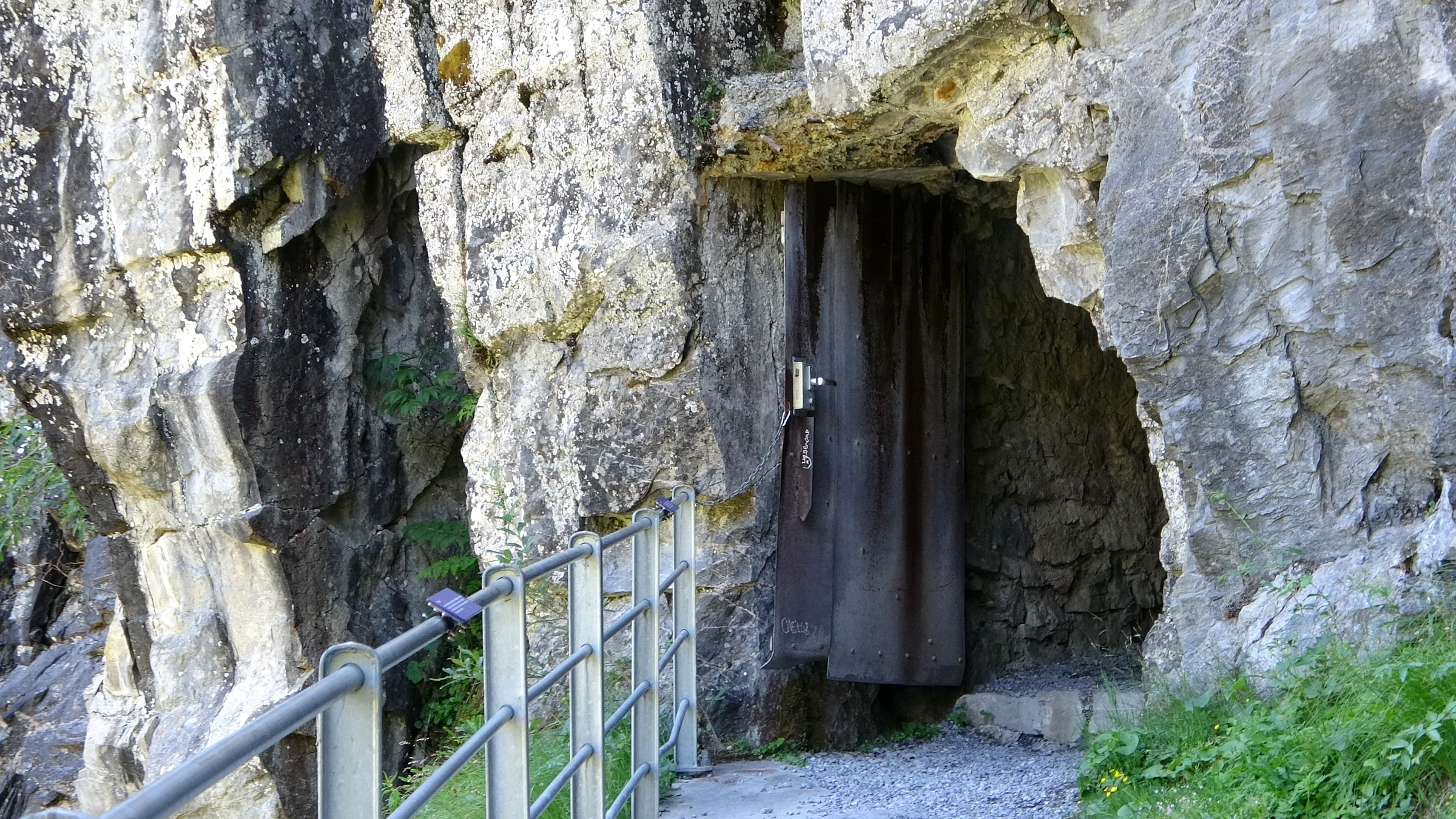 Holztür am Eingang eines Felstunnels auf dem Weg in die Gletscherschlucht Rosenlaui