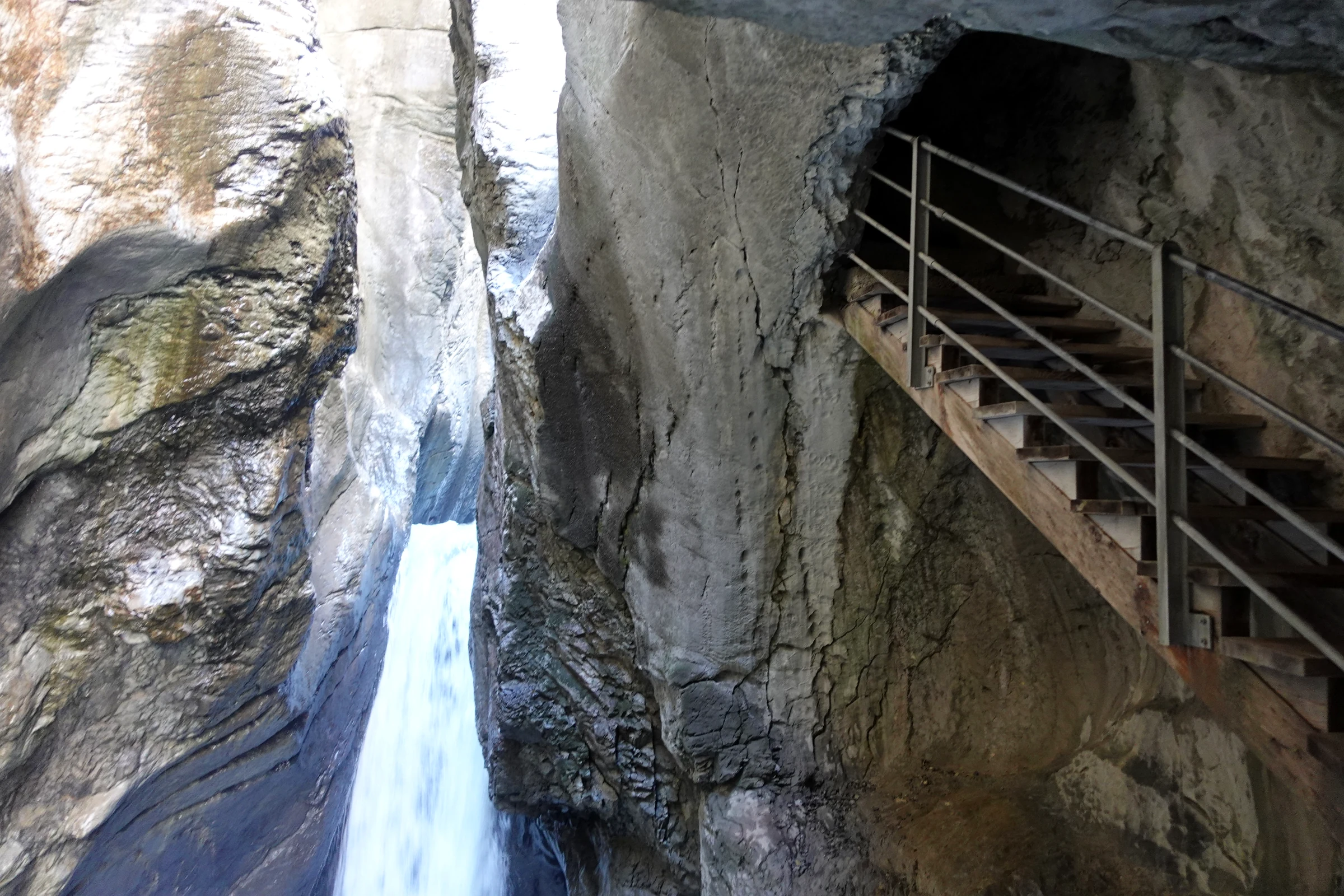 Stahltreppe an der Felswand neben einem Wasserfall in der oberen Gletscherschlucht Rosenlaui