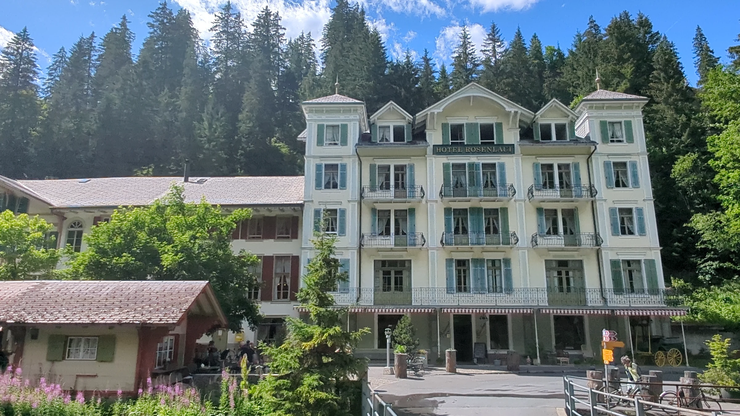 Belle-Époque-Fassade des Hotels Rosenlaui mit grünen Fensterläden und Balkonen vor dem Bergwald