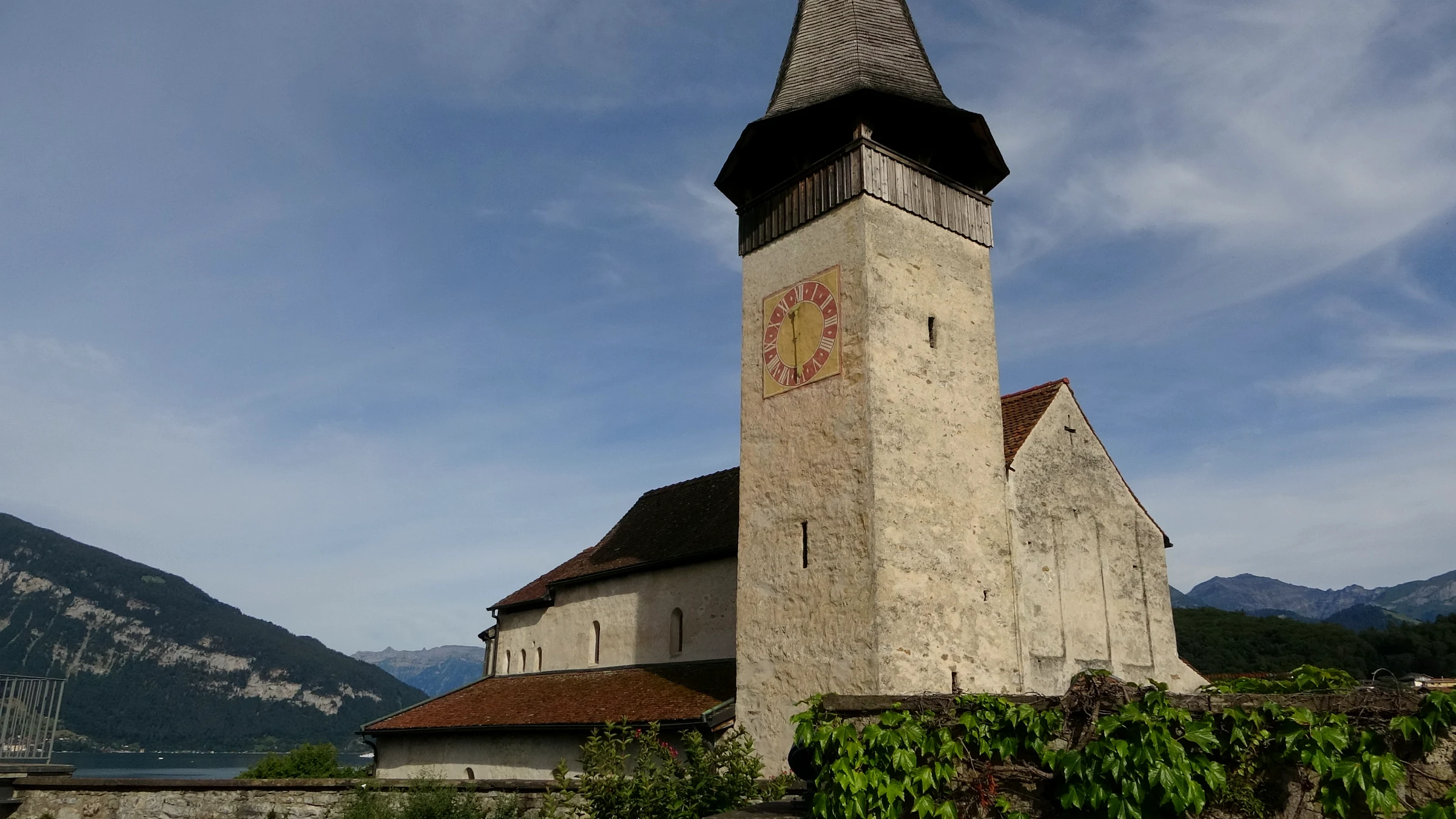 Turm der romanischen Schlosskirche Spiez mit Thunersee und Bergen im Hintergrund