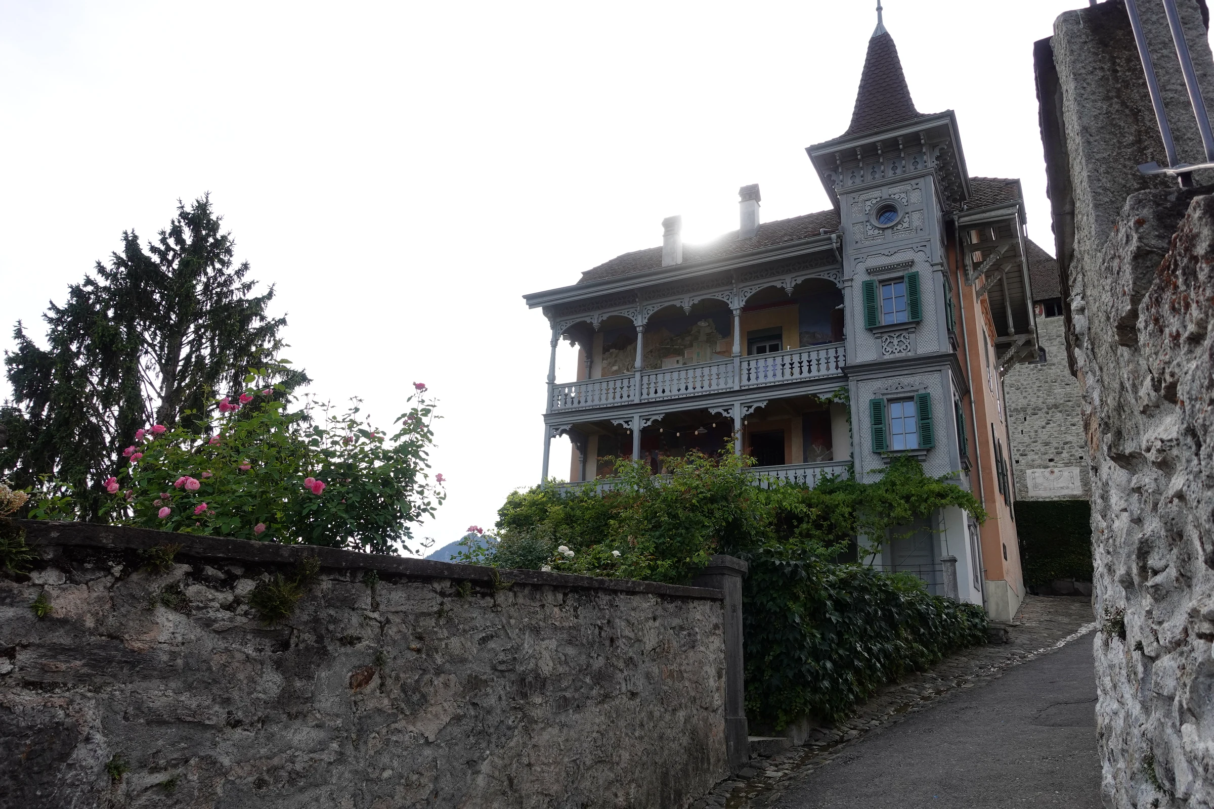 Alte Villa mit Türmchen und Holzbalkonen an einer schmalen Gasse unterhalb von Schloss Spiez