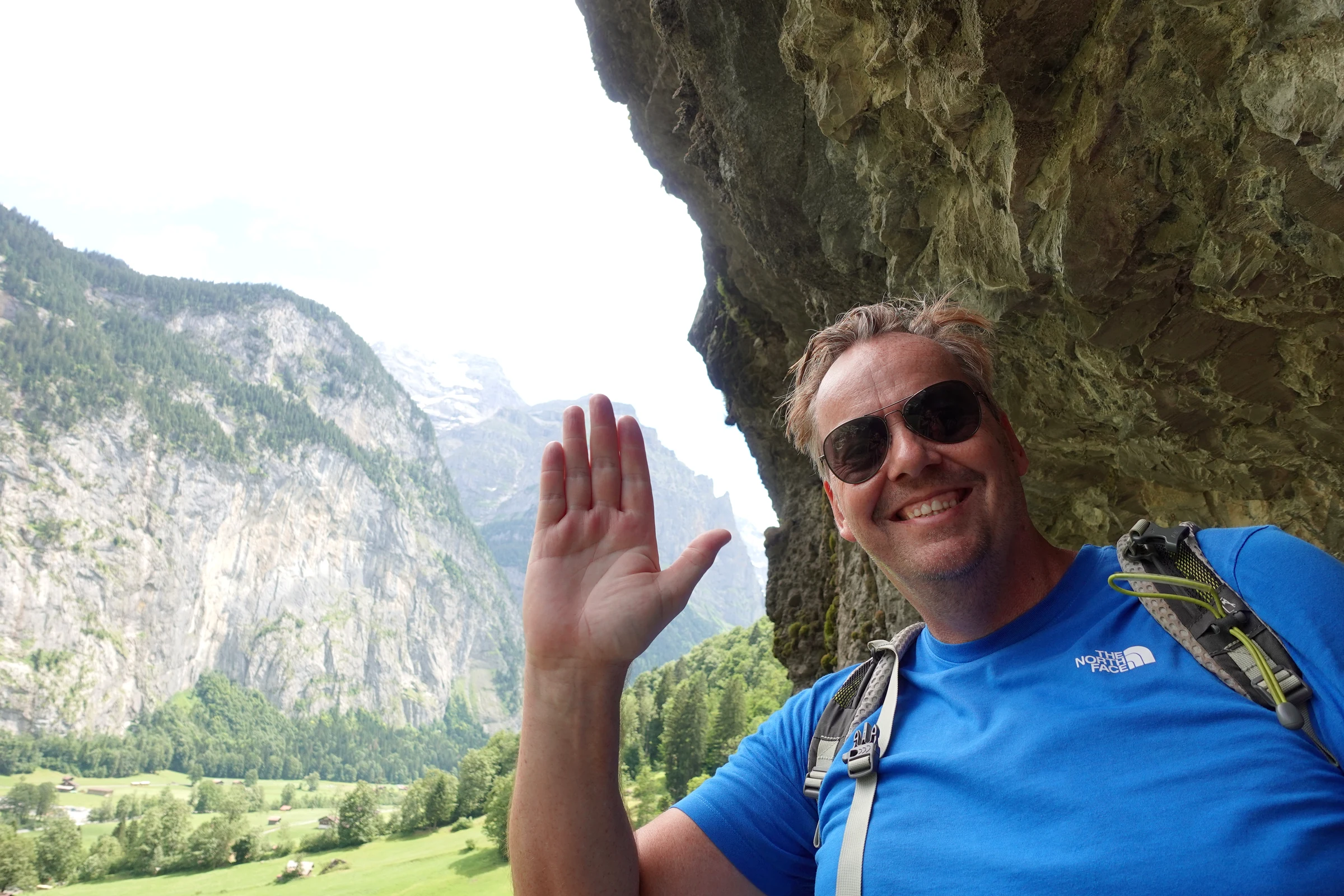 Autor Alexander Haselhoff winkt in der Galerie des Staubbachfalls unter dem Felsüberhang, dahinter das Lauterbrunnental