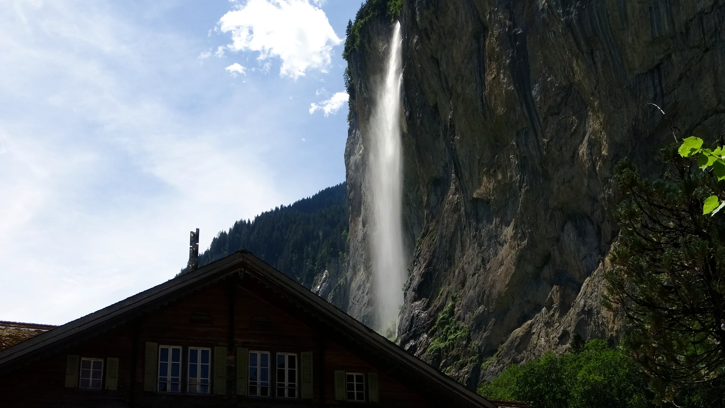 Staubbachfall über dem dunklen Holzdach eines alten Chalets in Lauterbrunnen
