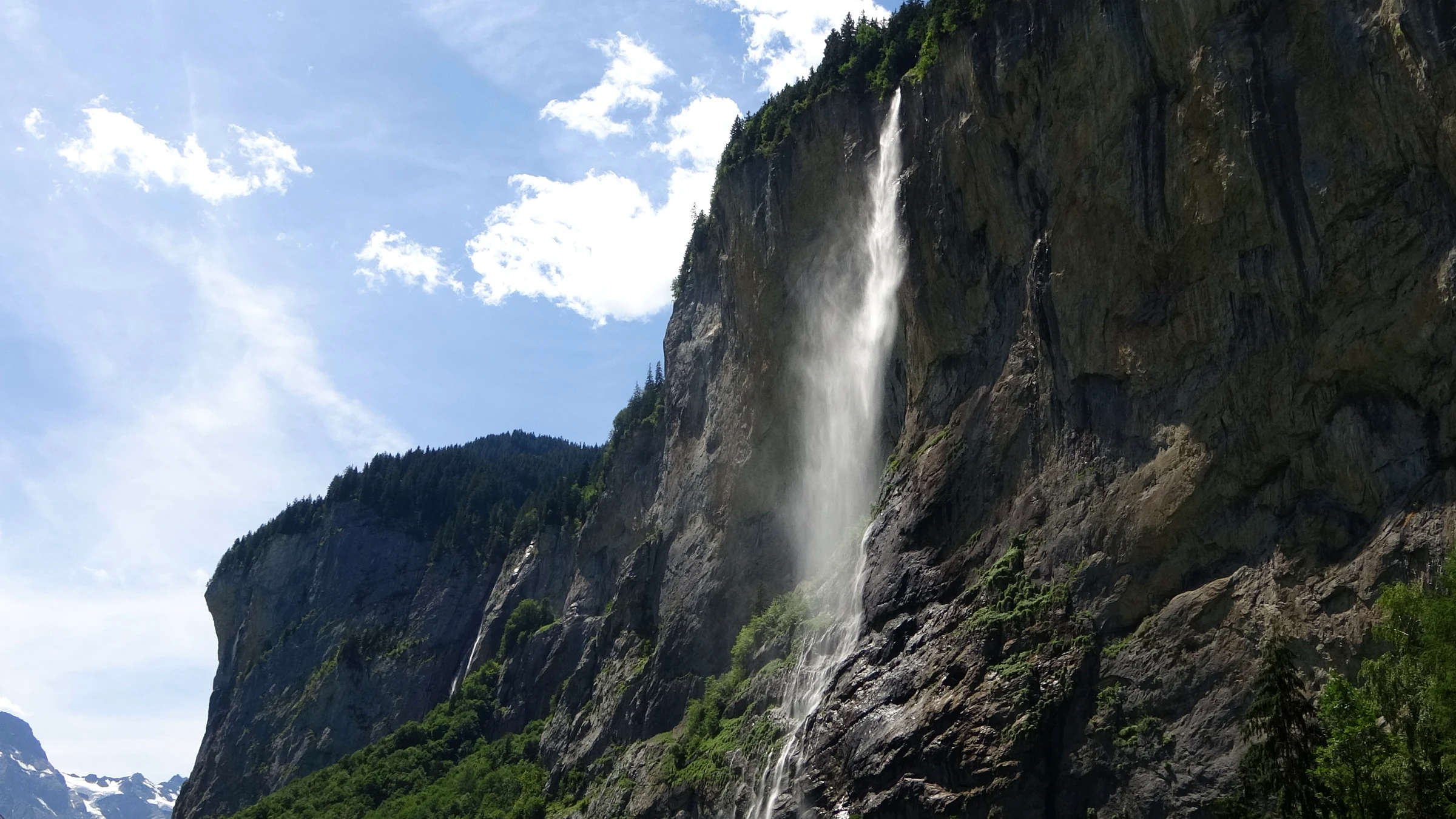 Der ganze 297 Meter hohe Staubbachfall an der grauen Felswand unter blauem Himmel