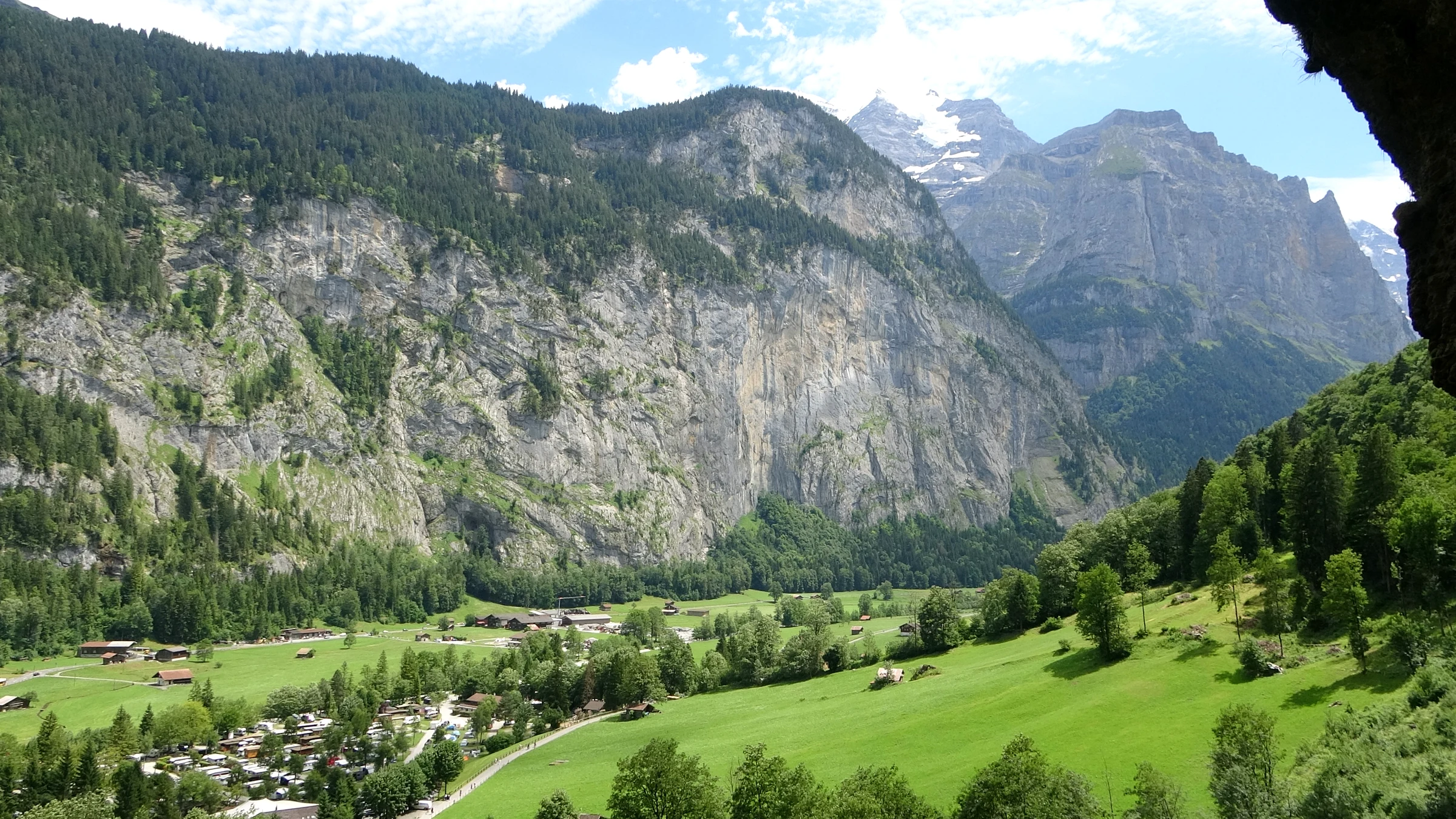 Blick aus der Staubbach-Galerie unter dem Felsüberhang ins grüne Lauterbrunnental bis zu verschneiten Gipfeln