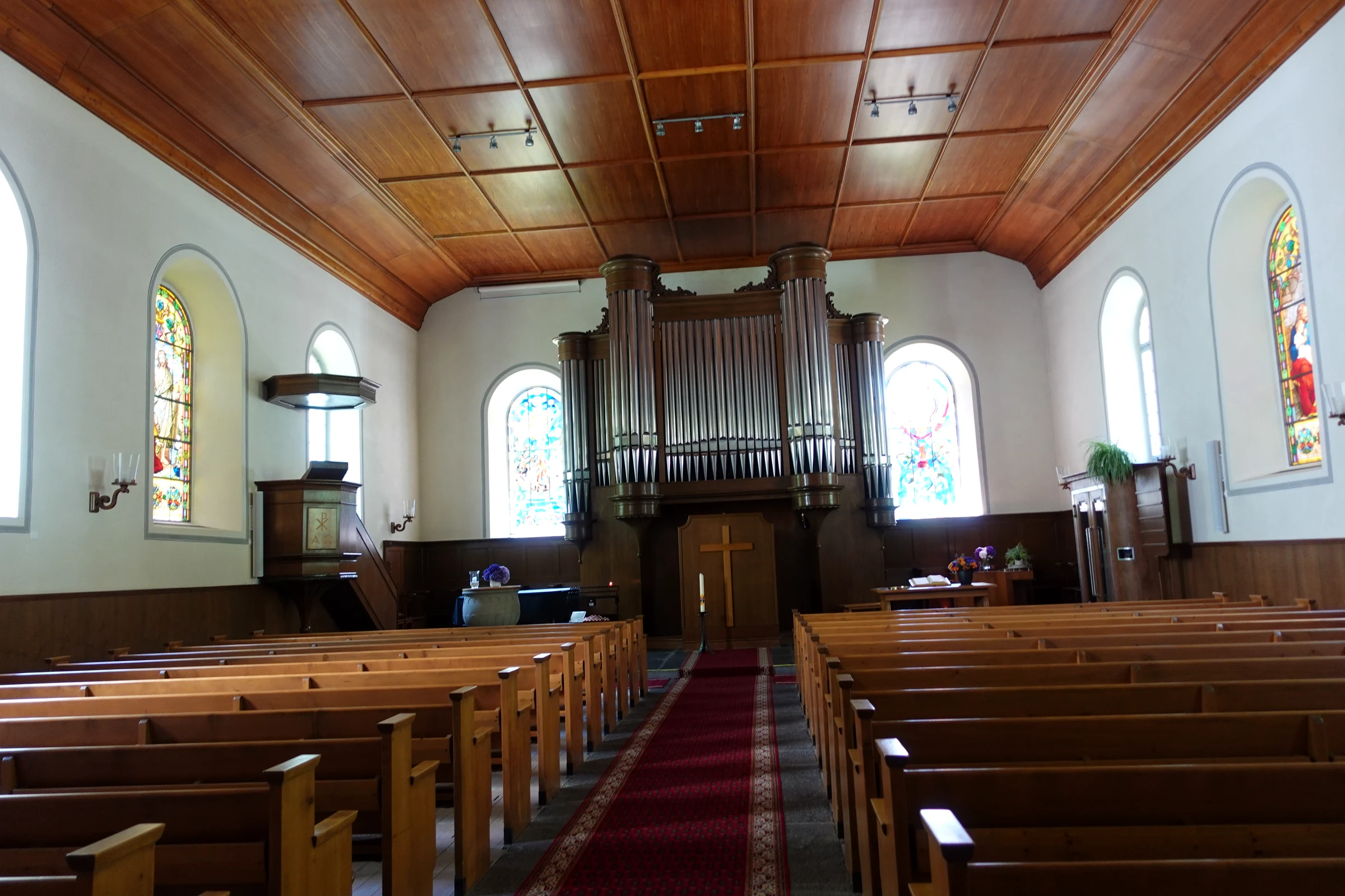 Innenraum der reformierten Kirche Lauterbrunnen mit Holzdecke, Orgel und Glasfenstern