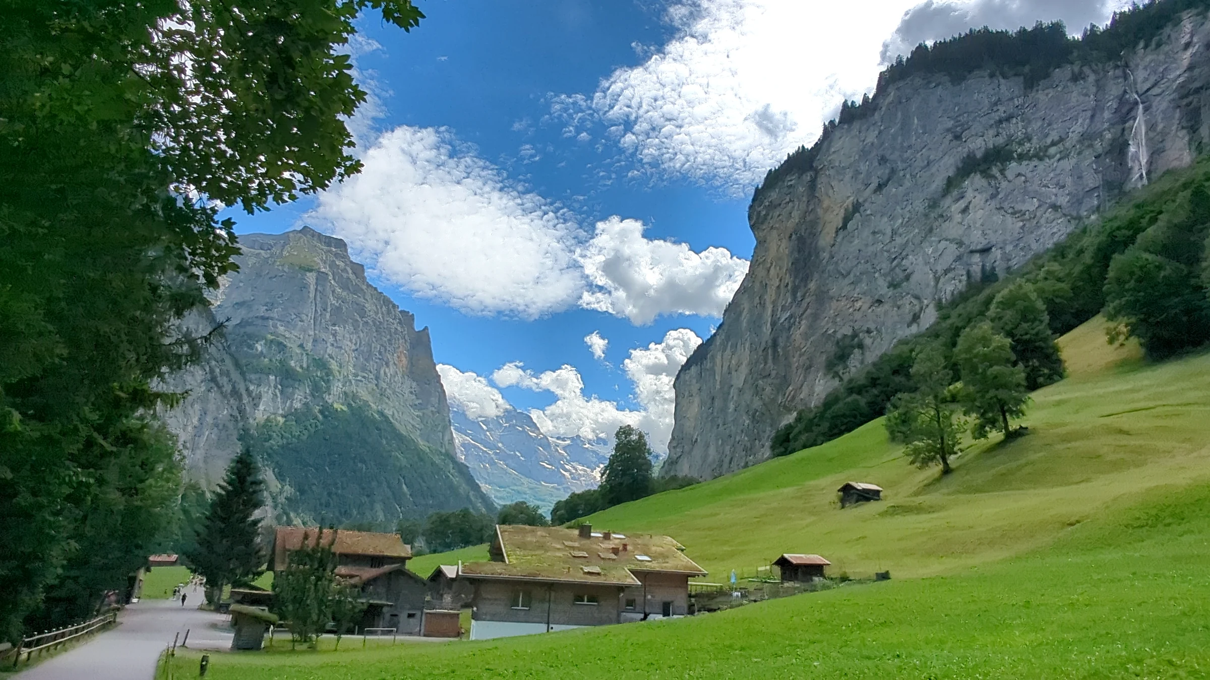 Grüne Wiesen und Bauernhäuser im Lauterbrunnental zwischen steilen Felswänden südlich des Dorfes