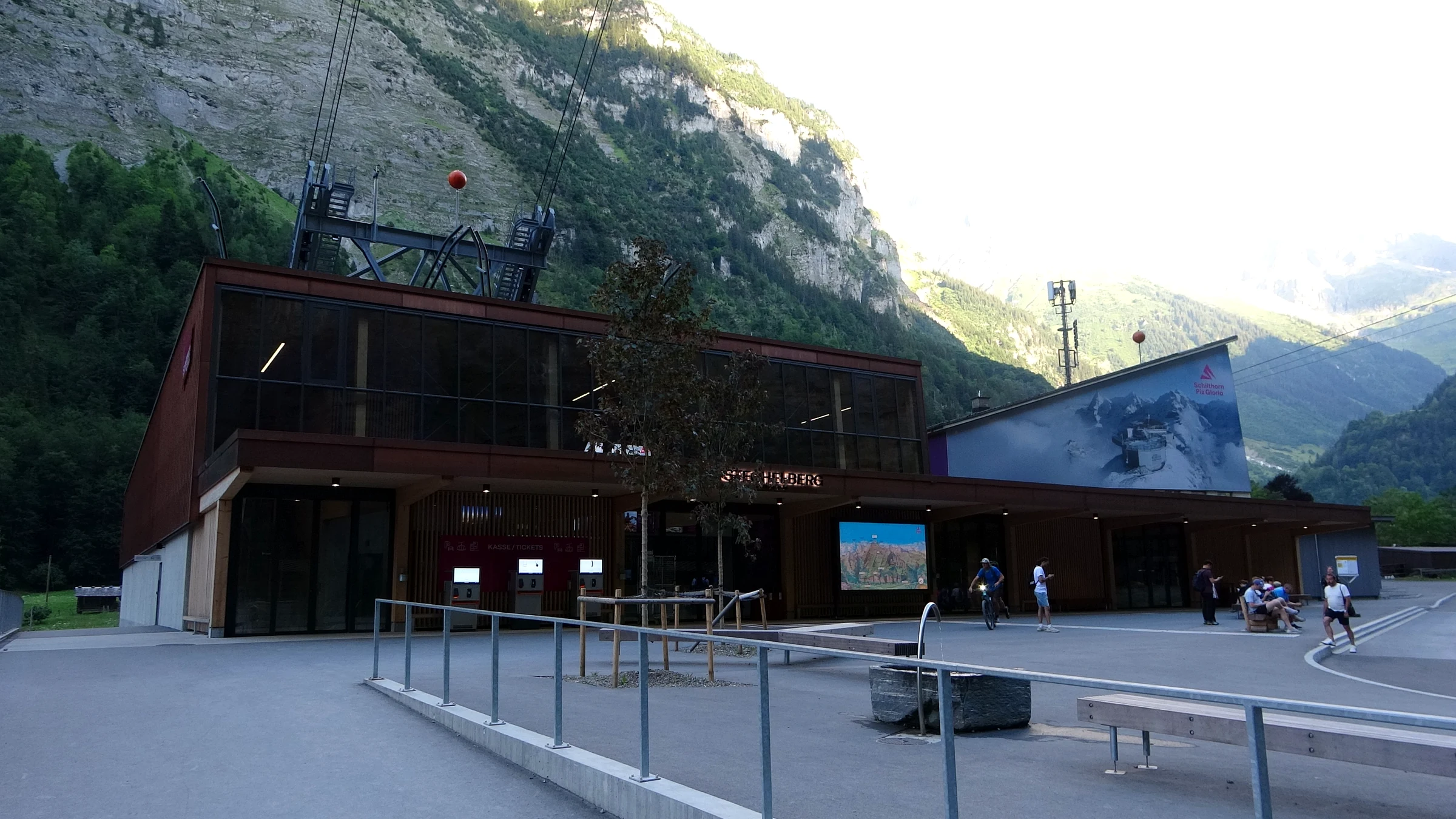 Modern Schilthornbahn valley station in Stechelberg with a large forecourt and the rock wall behind