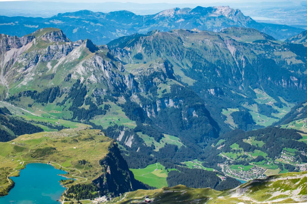 Blick vom Titlis hinunter auf den türkisfarbenen Trübsee, grüne Alpweiden und das Engelberger Tal