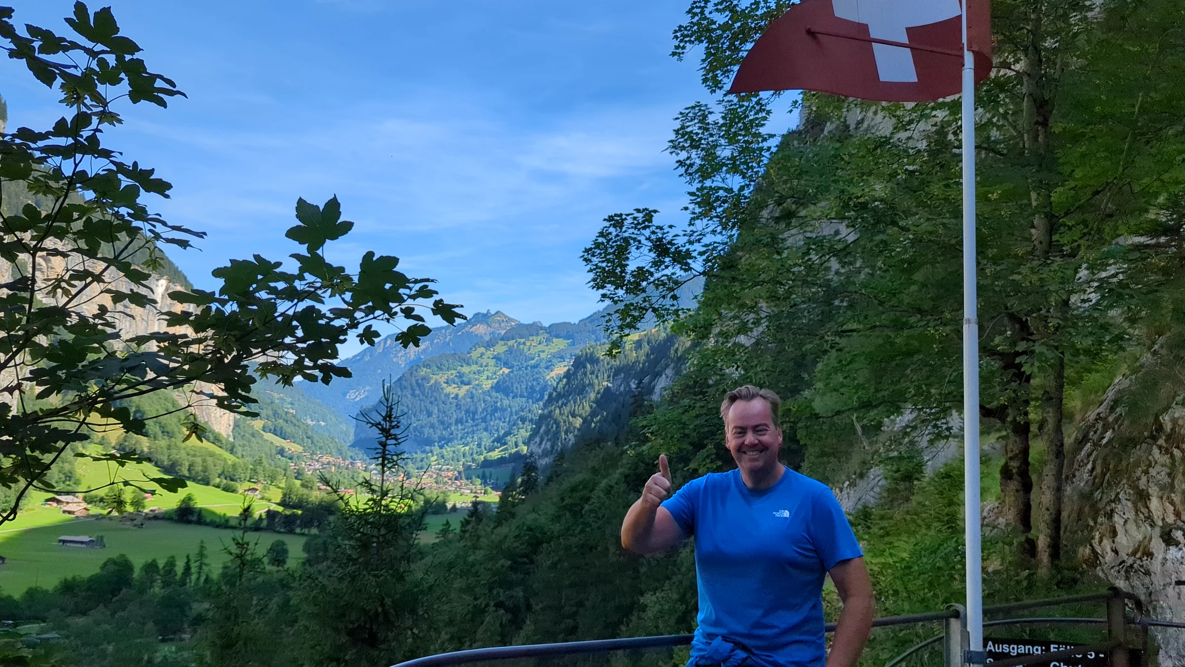 Autor Alexander Haselhoff am Weg bei den Trümmelbachfällen mit Schweizer Fahne und Blick ins Lauterbrunnental