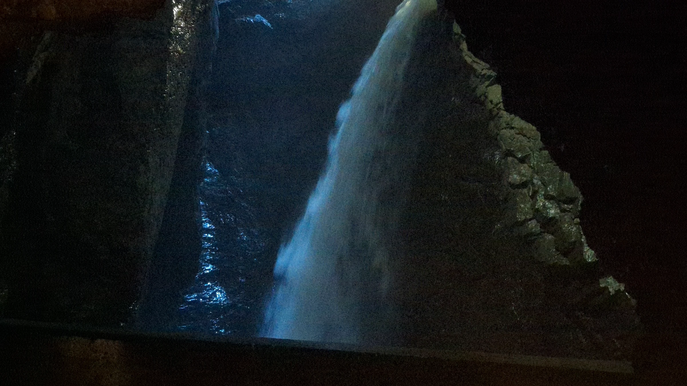 Angestrahlter Wasserfall in einer dunklen Felshöhle der oberen Trümmelbachfälle