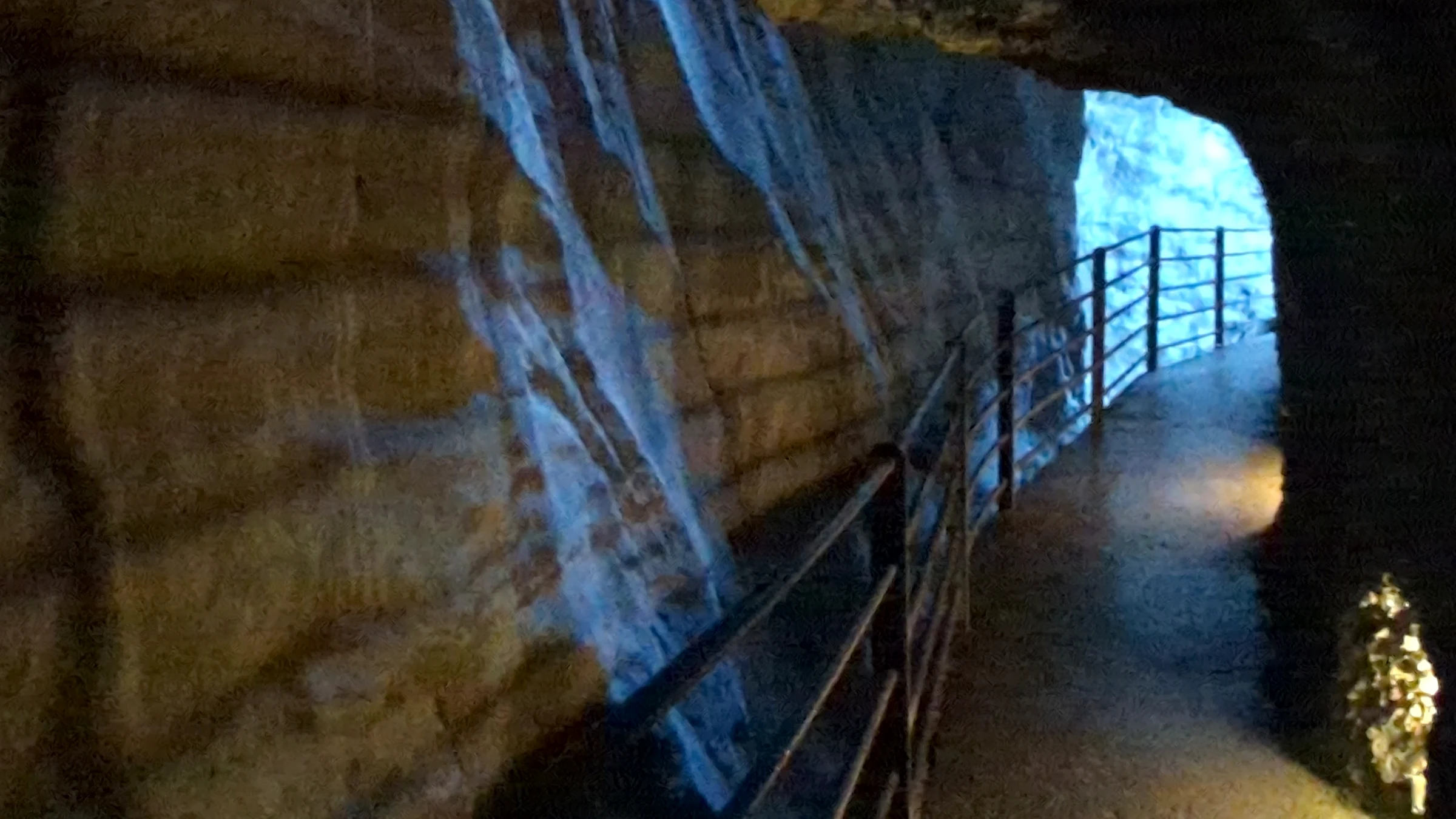 Blau beleuchtete Felsgalerie mit Geländer in der Trümmelbachschlucht