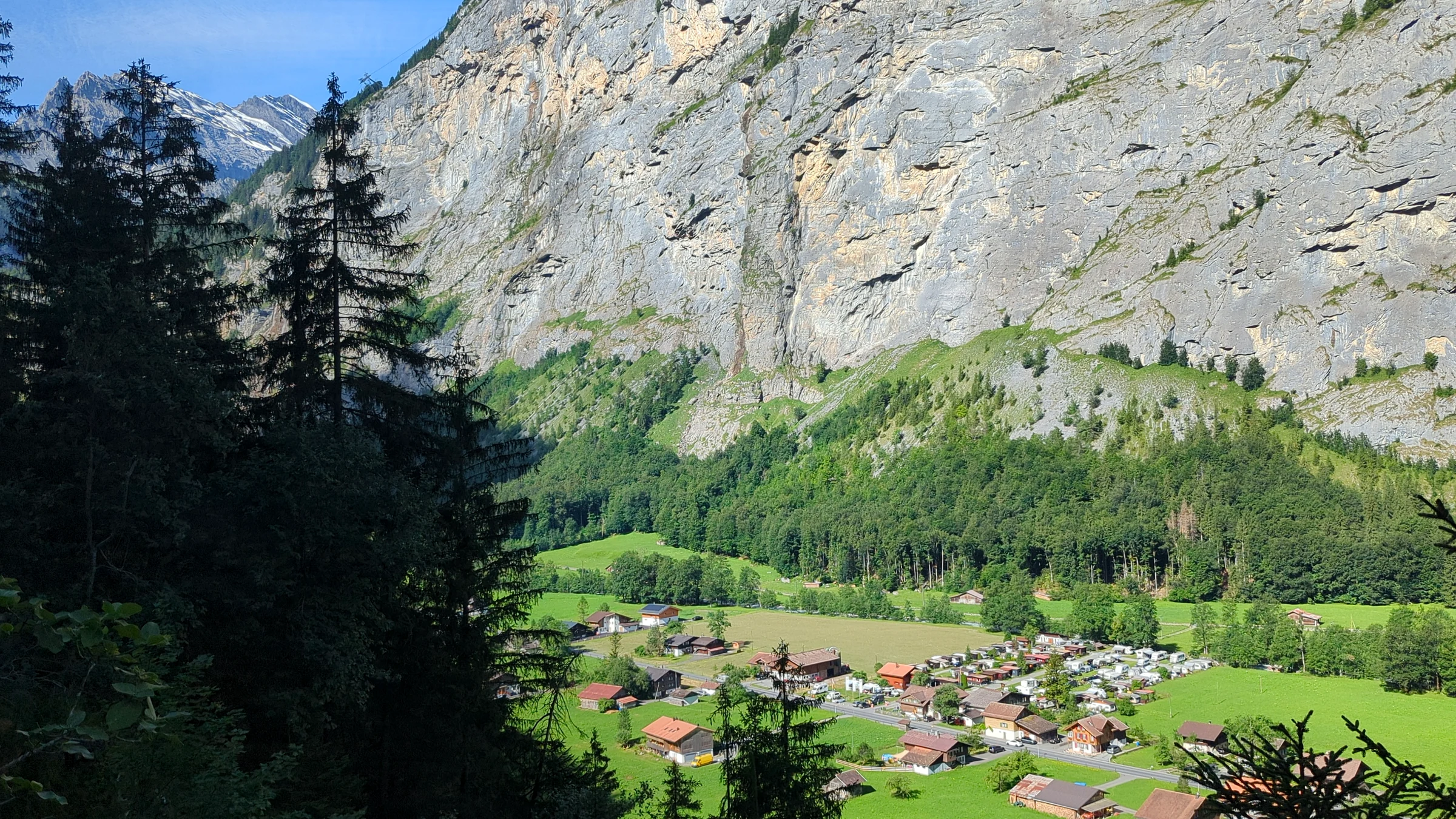 View from the Trümmelbach Falls path across the Lauterbrunnen Valley floor to chalets and the opposite rock wall